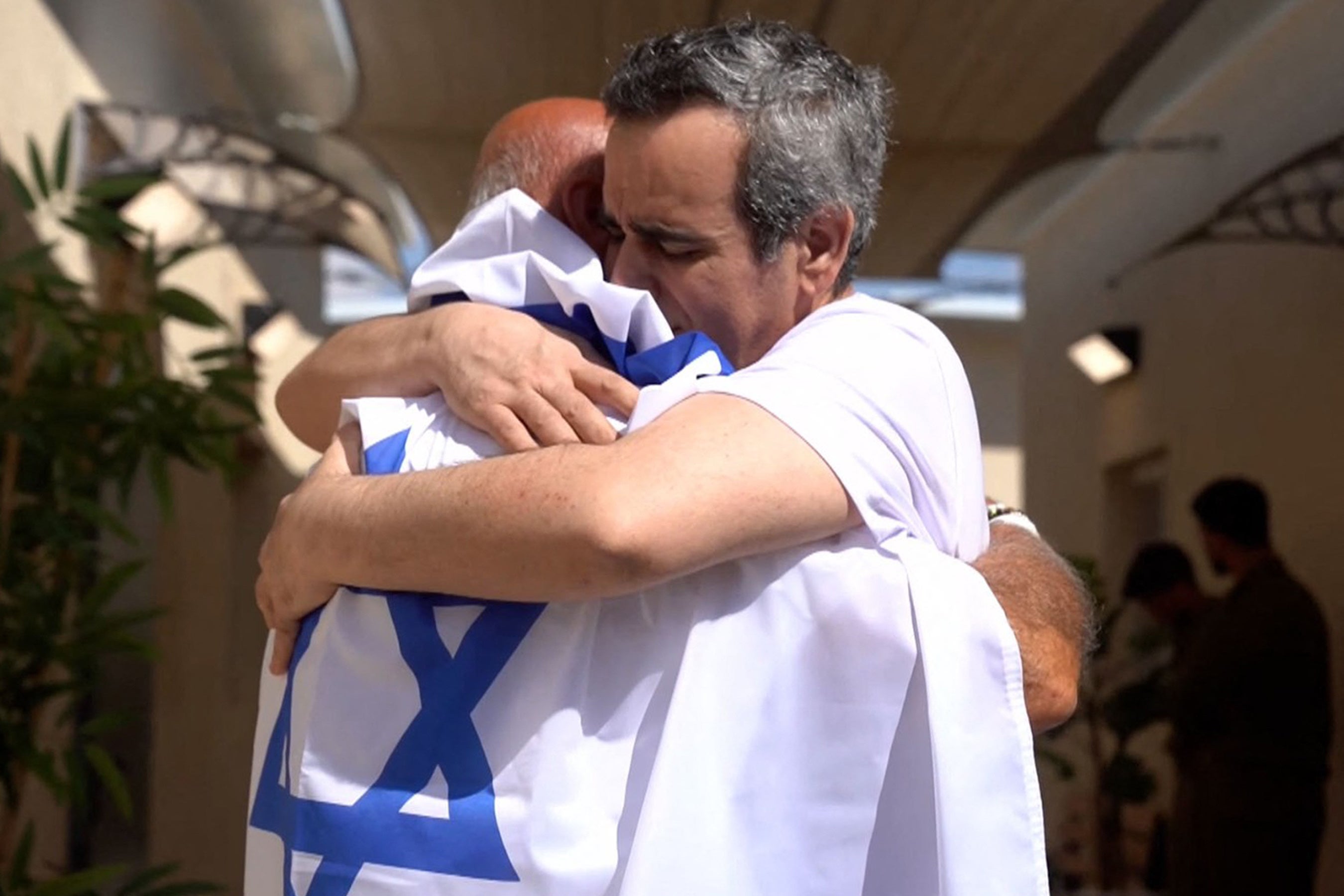 Captive Omri Miran, right, reunited by a member of his family draped in an Israeli flag