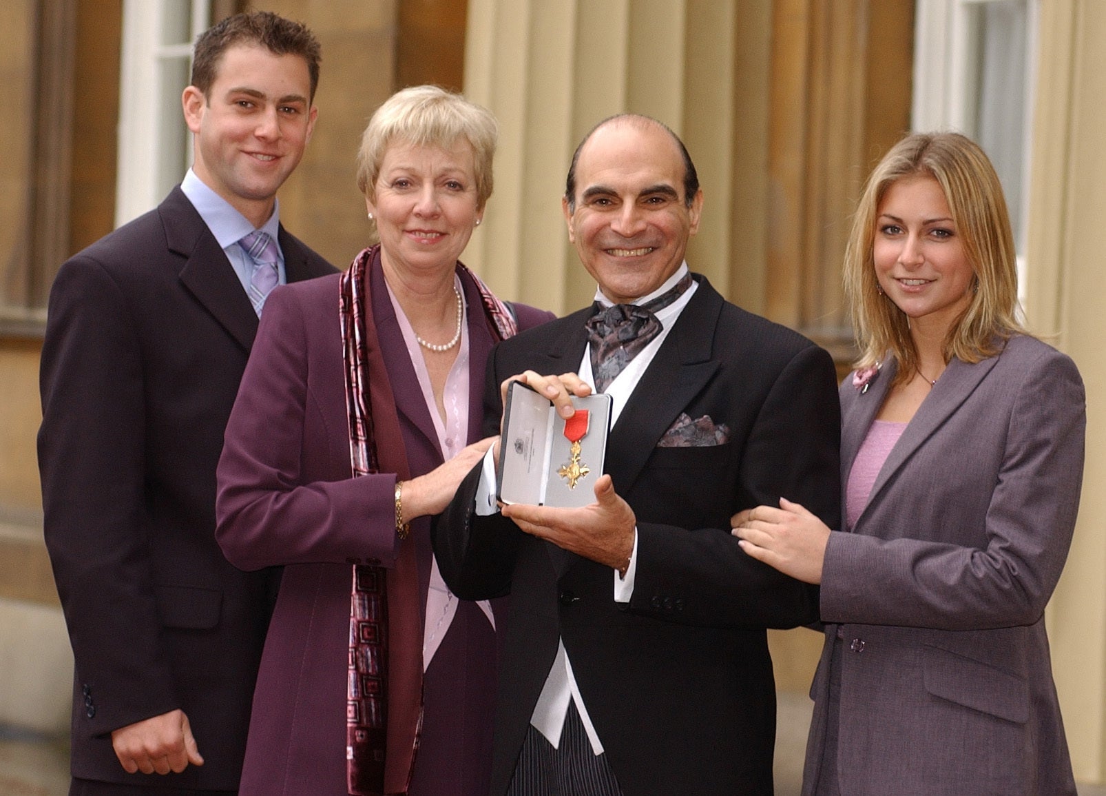 Sir David Suchet holding his OBE medal and posing for a picture with his family