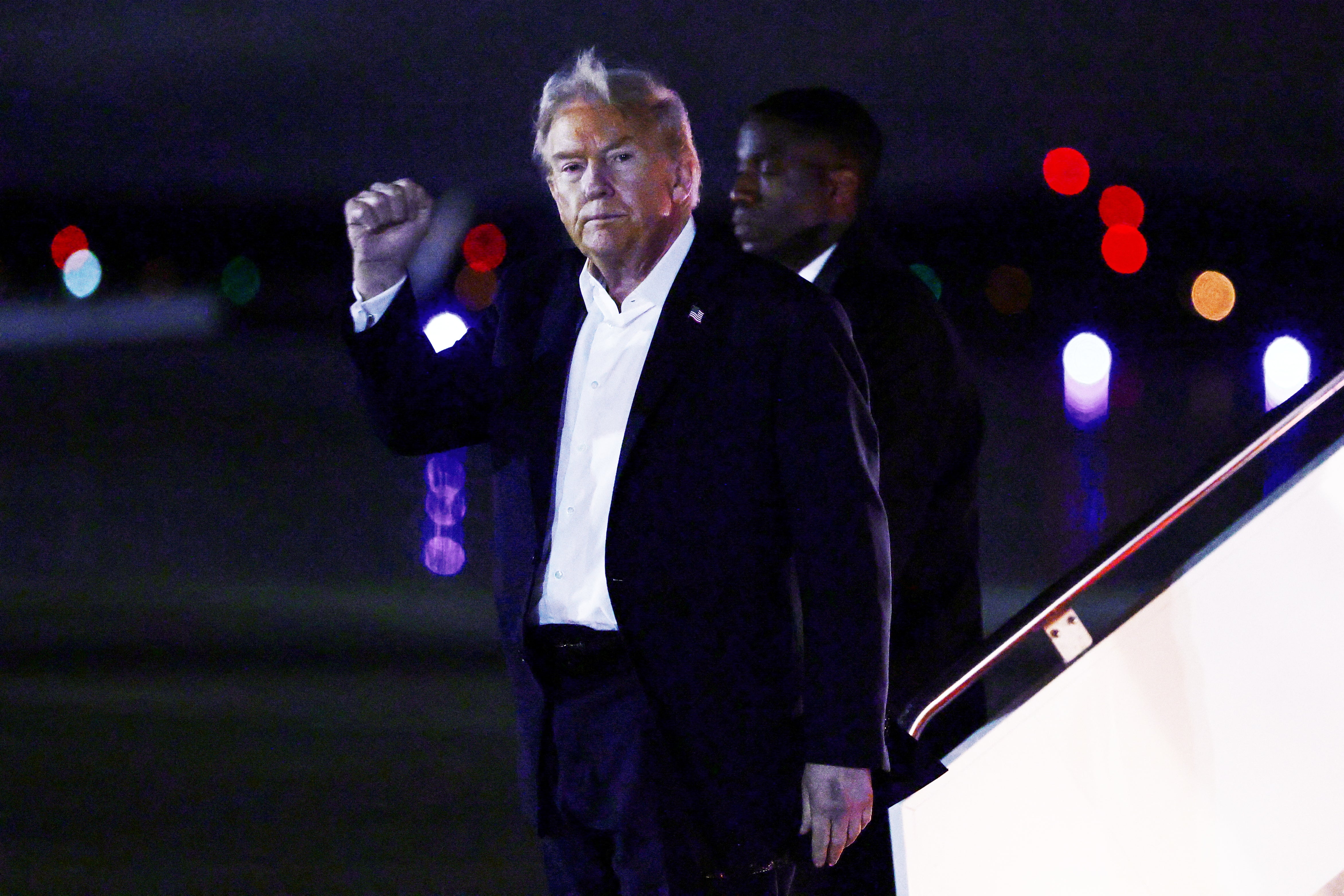 Donald Trump gestures as he disembarks Air Force Once after returning from the summit in Egypt
