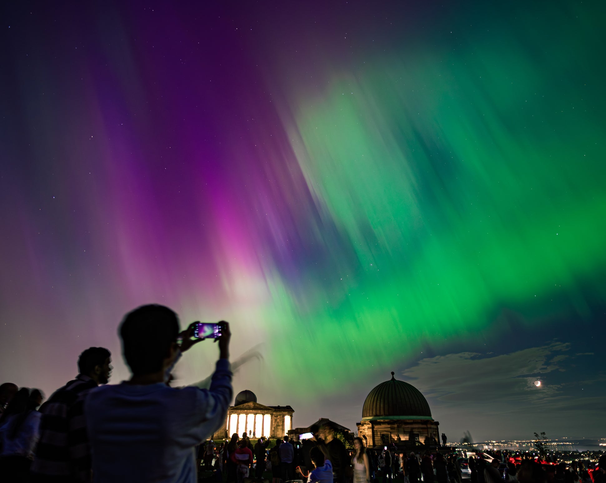 <p>Spectators on Calton Hill in Edinburgh, UK, watch the northern lights</p>