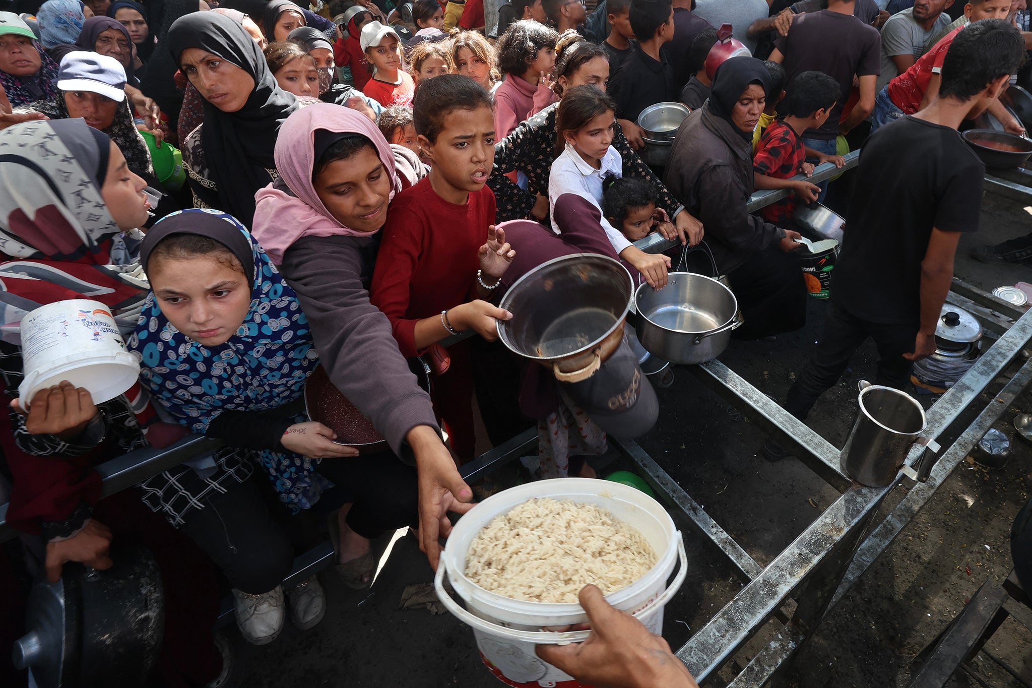 Palestinians gather to receive food portions from a charity kitchen on 15 October