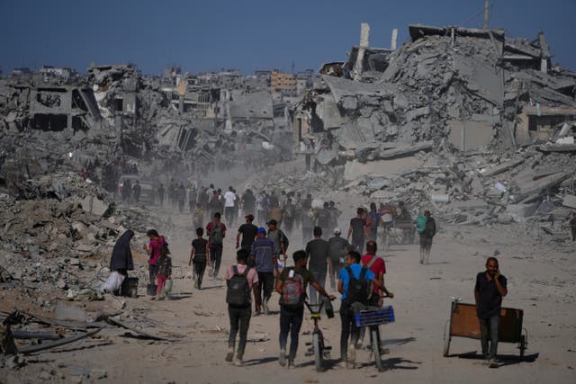 <p>Displaced Palestinians walk past destroyed buildings as they return to their homes in the Zeitoun neighborhood of Gaza City</p>