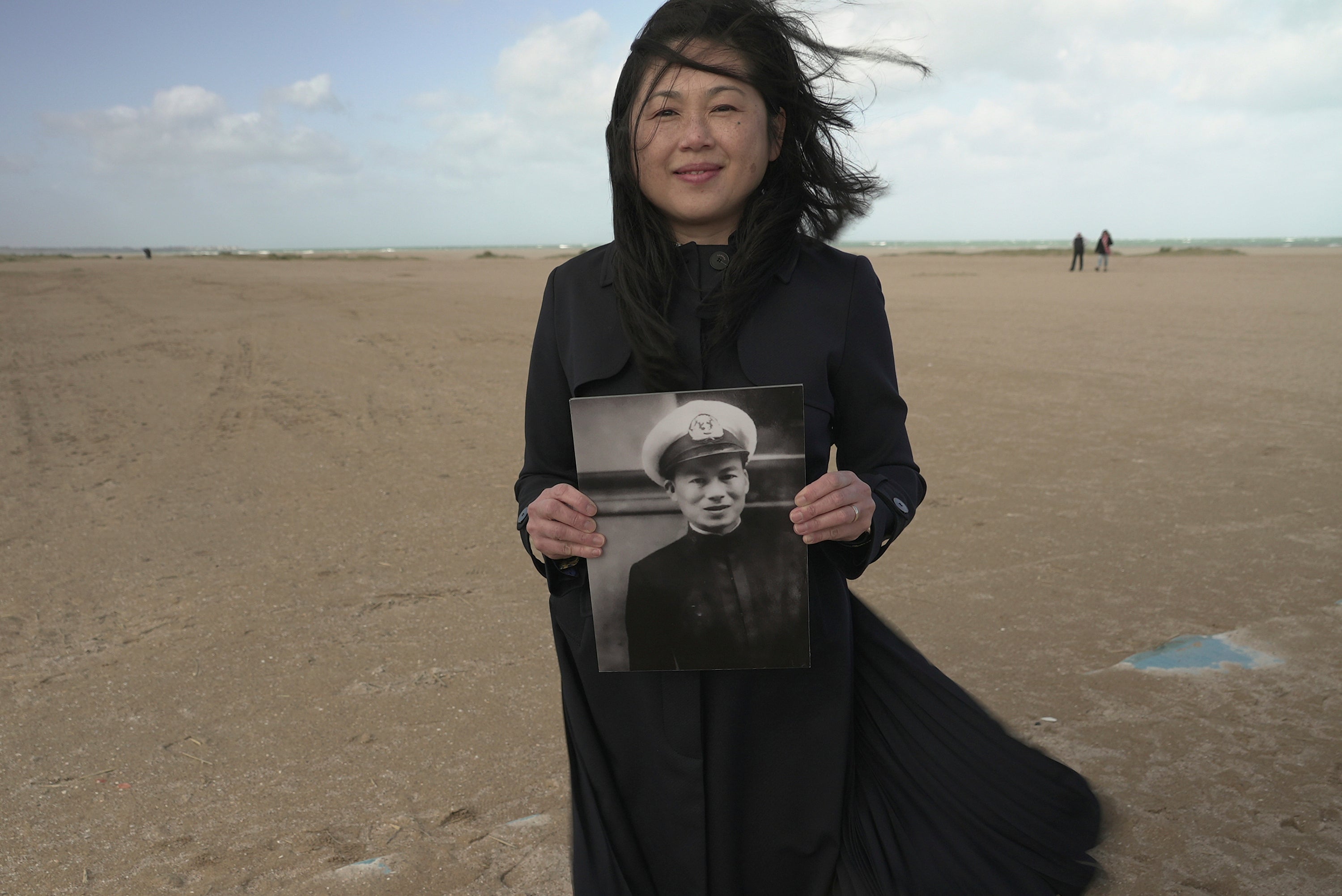 Sau Ying Lam poses with a photo of her father Lam Ping-yu on the beach in Ouistreham, France, on Saturday Oct. 4, 2025. (AP Photo/John Leicester)