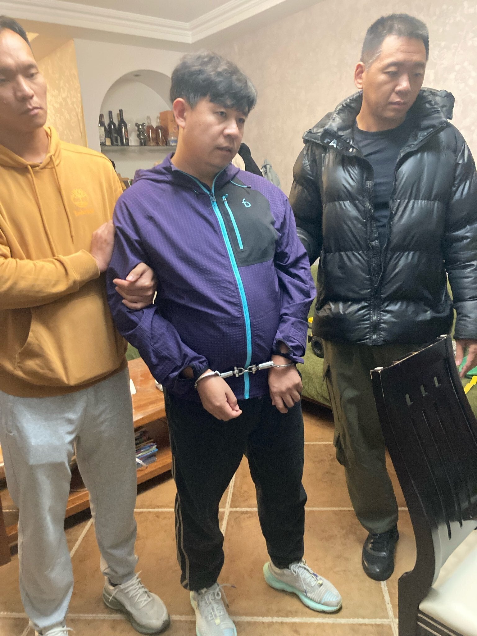 Pastor Sun Cong of Zion Church standing, wearing handcuffs, after being detained by police at his home in Beijing, China on 10 October 2025