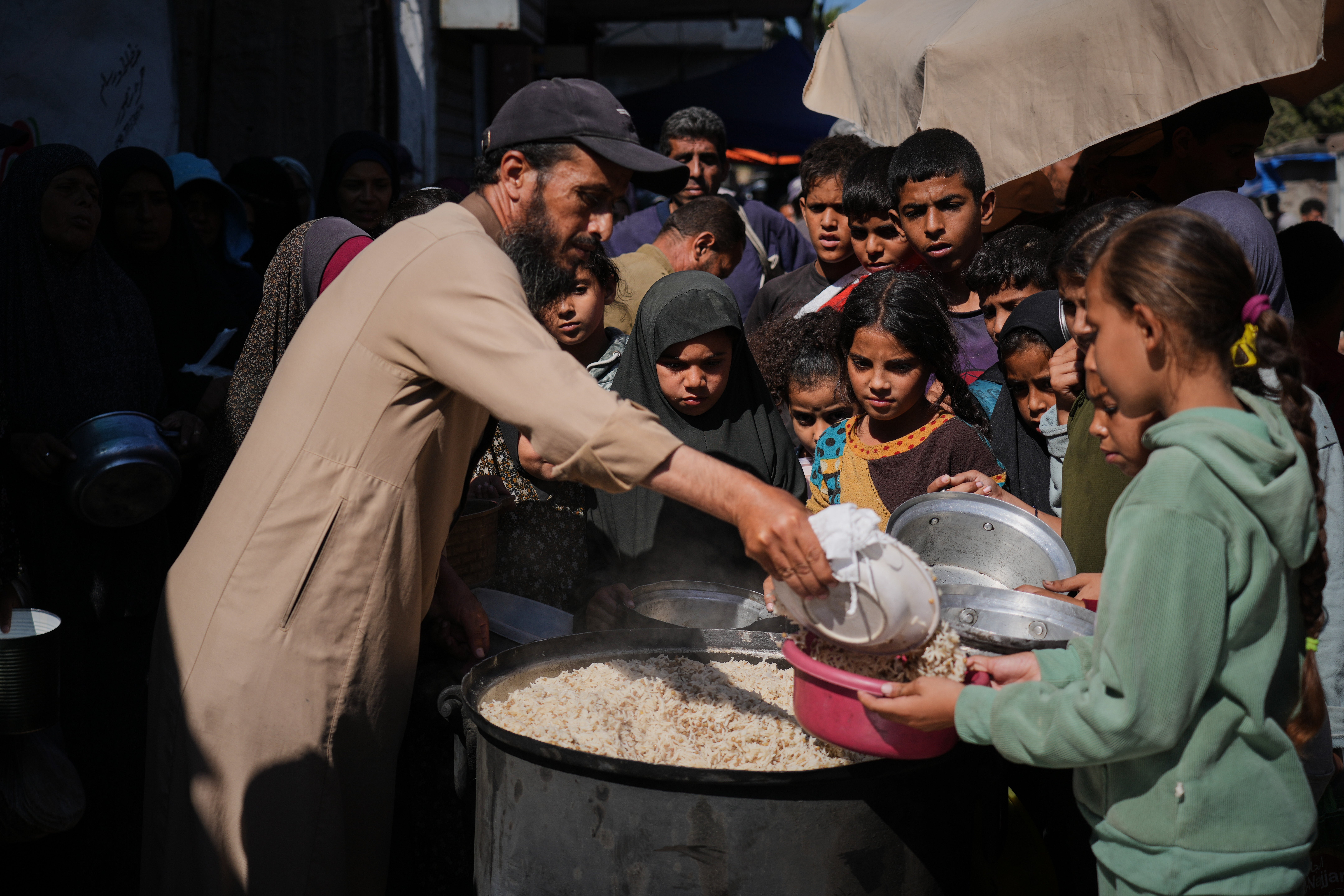 <p>Palestinians receive donated food at a community kitchen in Deir al-Balah, central Gaza Strip</p>