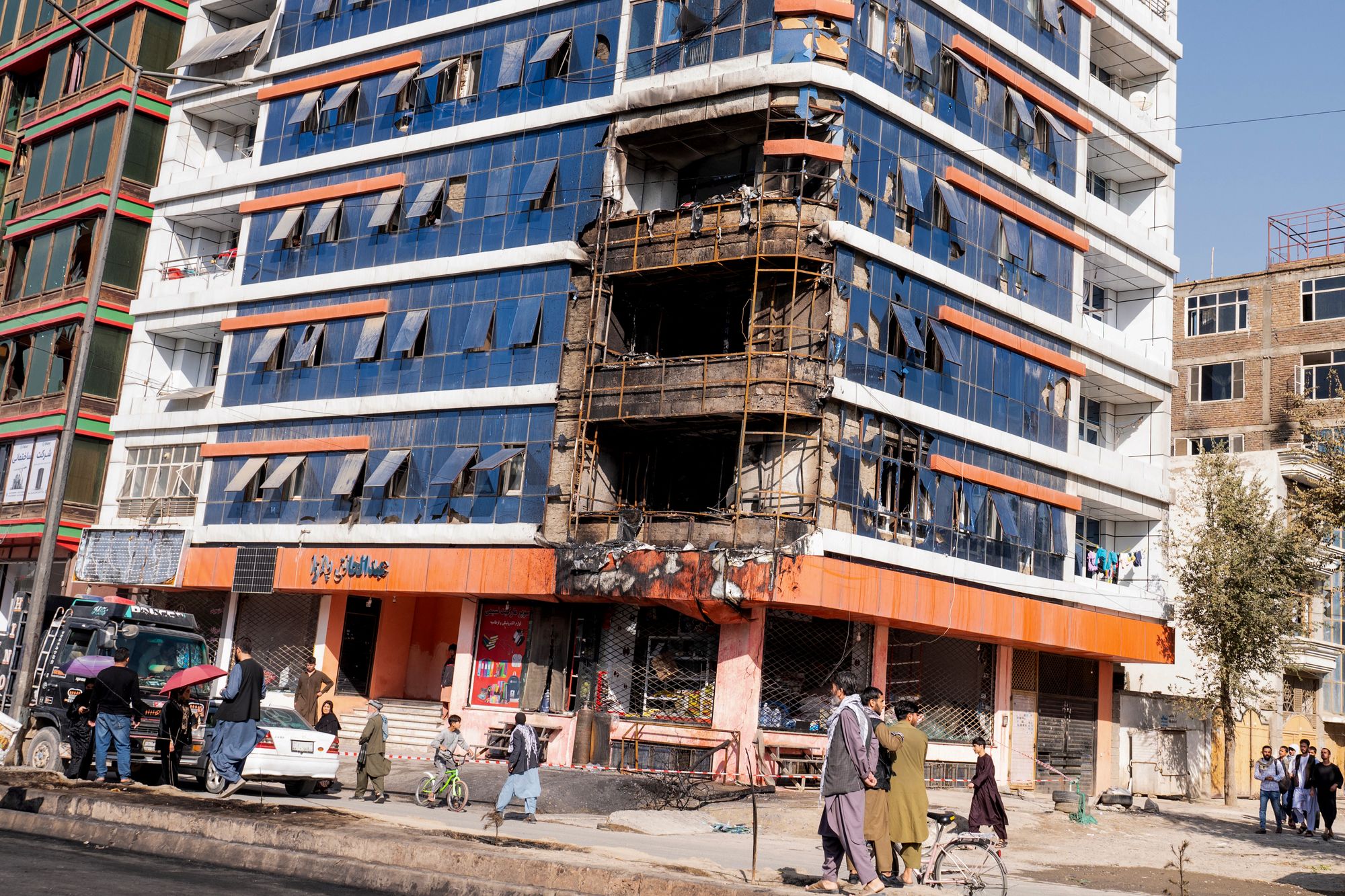 Afghan men walk past a damaged building following an explosion in Kabul, on 16 October 2025. At least five people were killed and 35 wounded in explosions on October 15 in Kabul, an Italian NGO which runs a hospital in the Afghan capital said, before a truce with Pakistan entered into effect