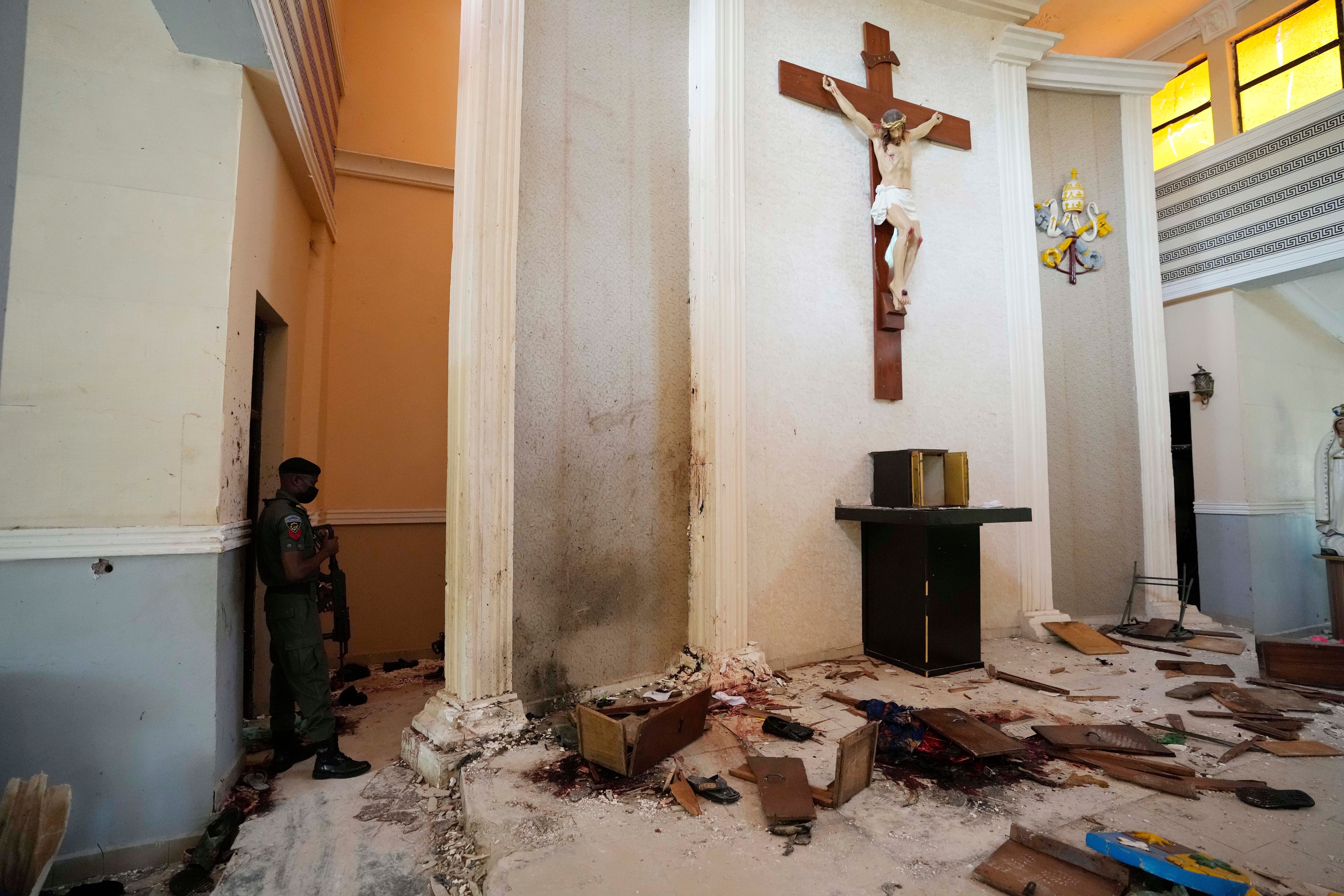 A police officer stands guard inside the St. Francis Catholic Church, a day after an attacked that targeted worshipers in Owo, Nigeria
