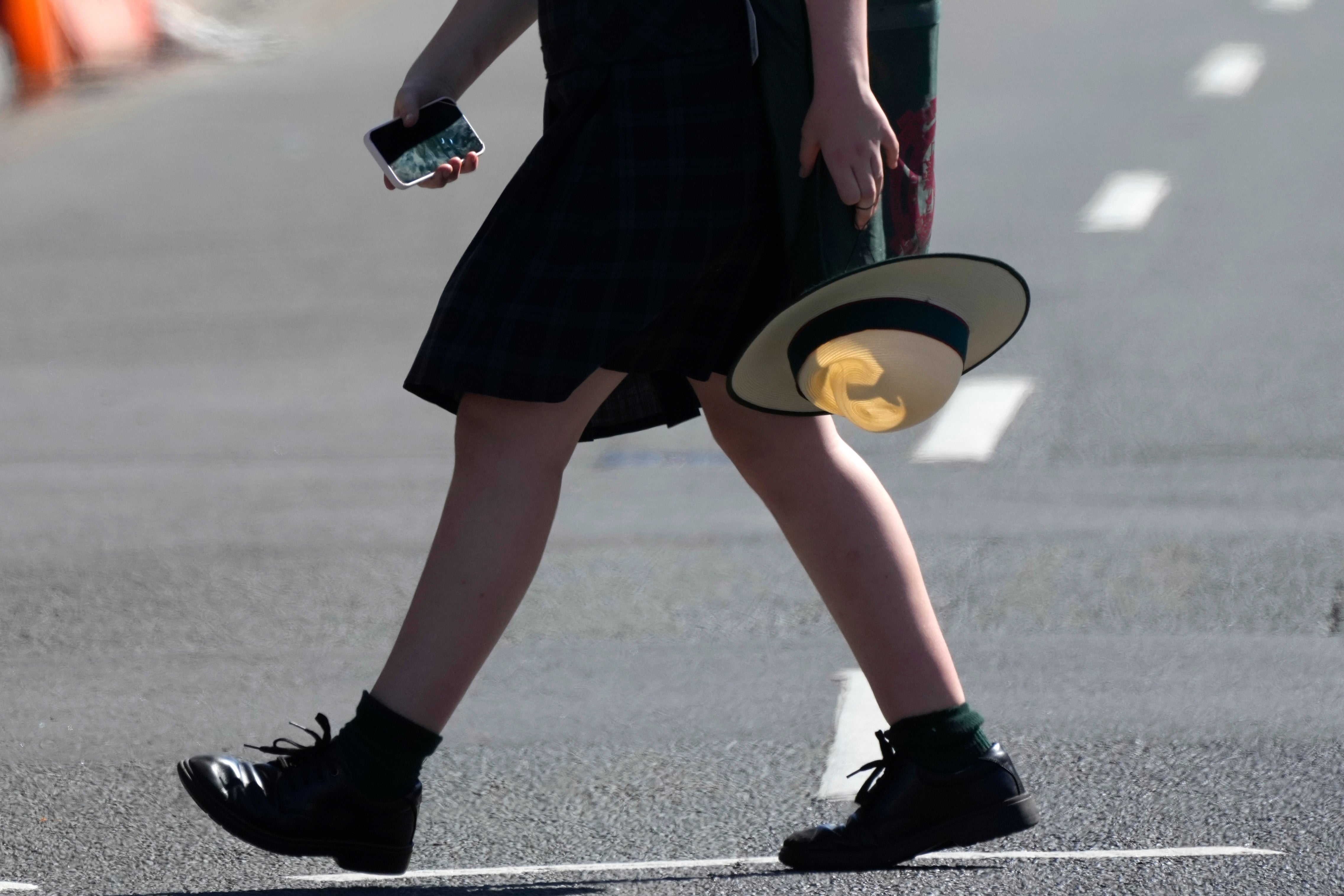 A school girl holds her phone while crossing a street in Sydney, on Nov. 8, 2024. (AP Photo/Rick Rycroft, File) Social Media