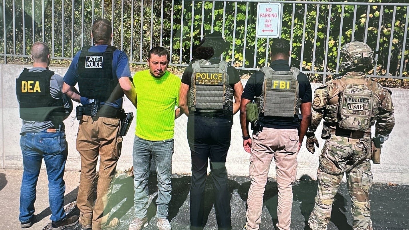 Police pose with Juan Espinoza-Martinez, whom officials allege is a Latin Kings gang member who called for the killing of Gregory Bovino, a top Border Patrol official