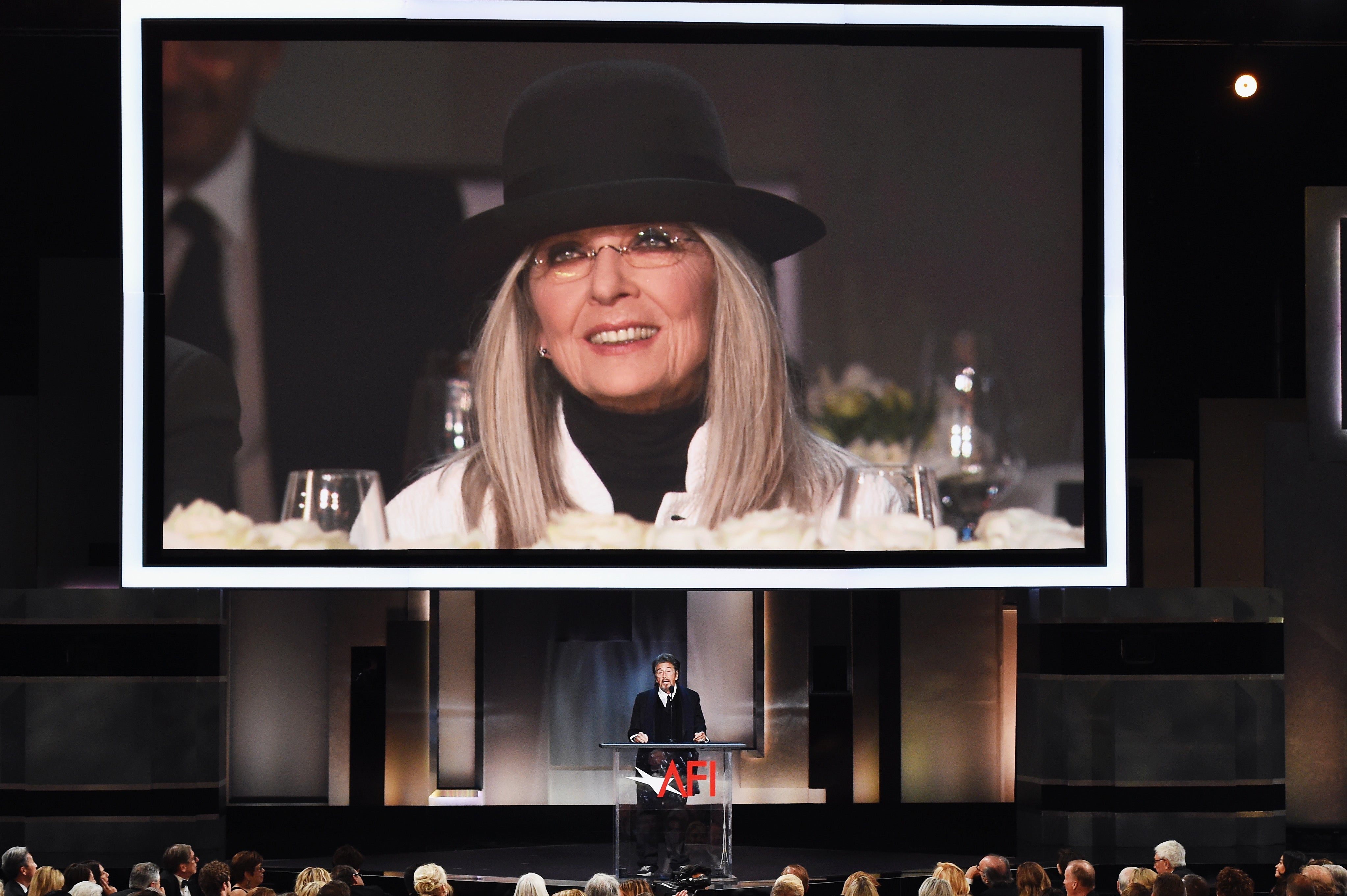 An image of Keaton is projected on a video screen while Pacino speaks onstage during the American Film Institute's 45th Life Achievement Award gala tribute to Keaton at the Dolby Theatre on June 8, 2017, in Hollywood, California