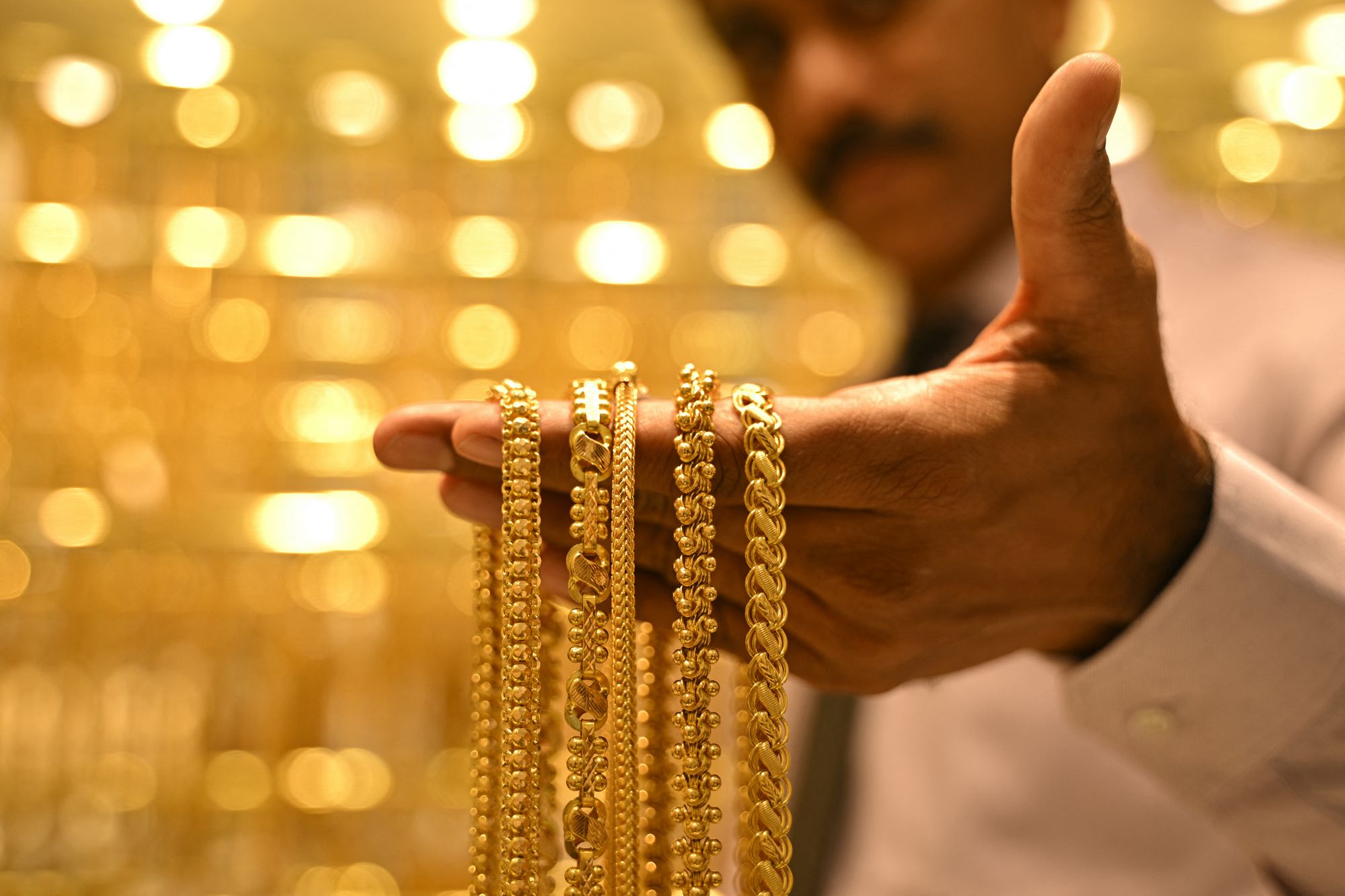 A salesman displays gold chains at a shop in India