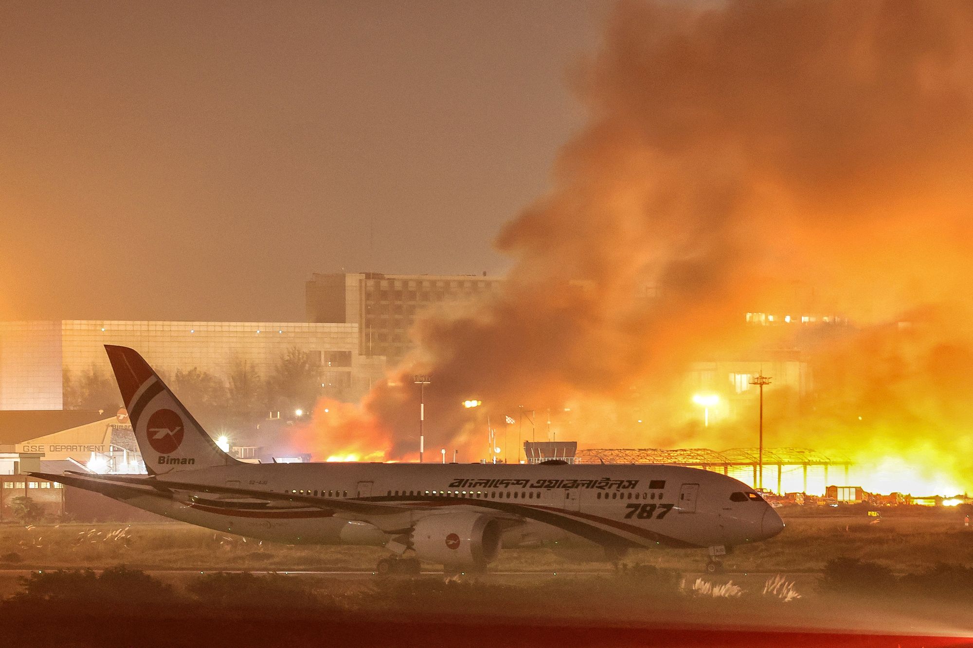 <p>An airline plane stands on the tarmac as firefighters try to extinguish a fire that broke out in the cargo section of Hazrat Shahjalal International Airport in Dhaka on October 18, 2025. (Photo by Maruf Rahman / AFP) / ALTERNATE CROP (Photo by MARUF RAHMAN/AFP via Getty Images)</p>