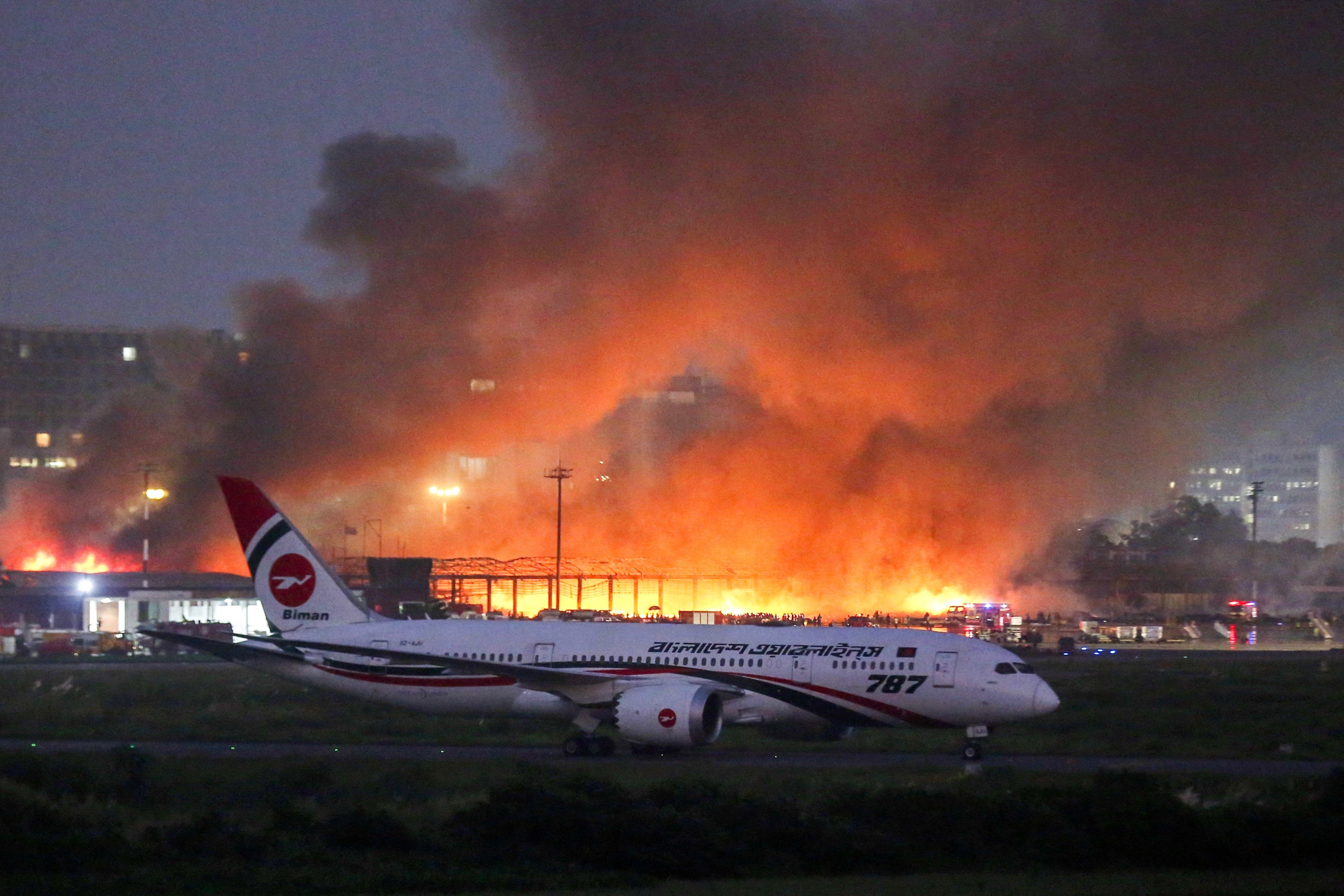 A passenger plane sits on the tarmac, as smoke rises from a fire, which broke out in the cargo bay of the Hazrat Shahjalal International Airport, in Dhaka, Bangladesh, October 18, 2025. REUTERS/Mehedi Hasan