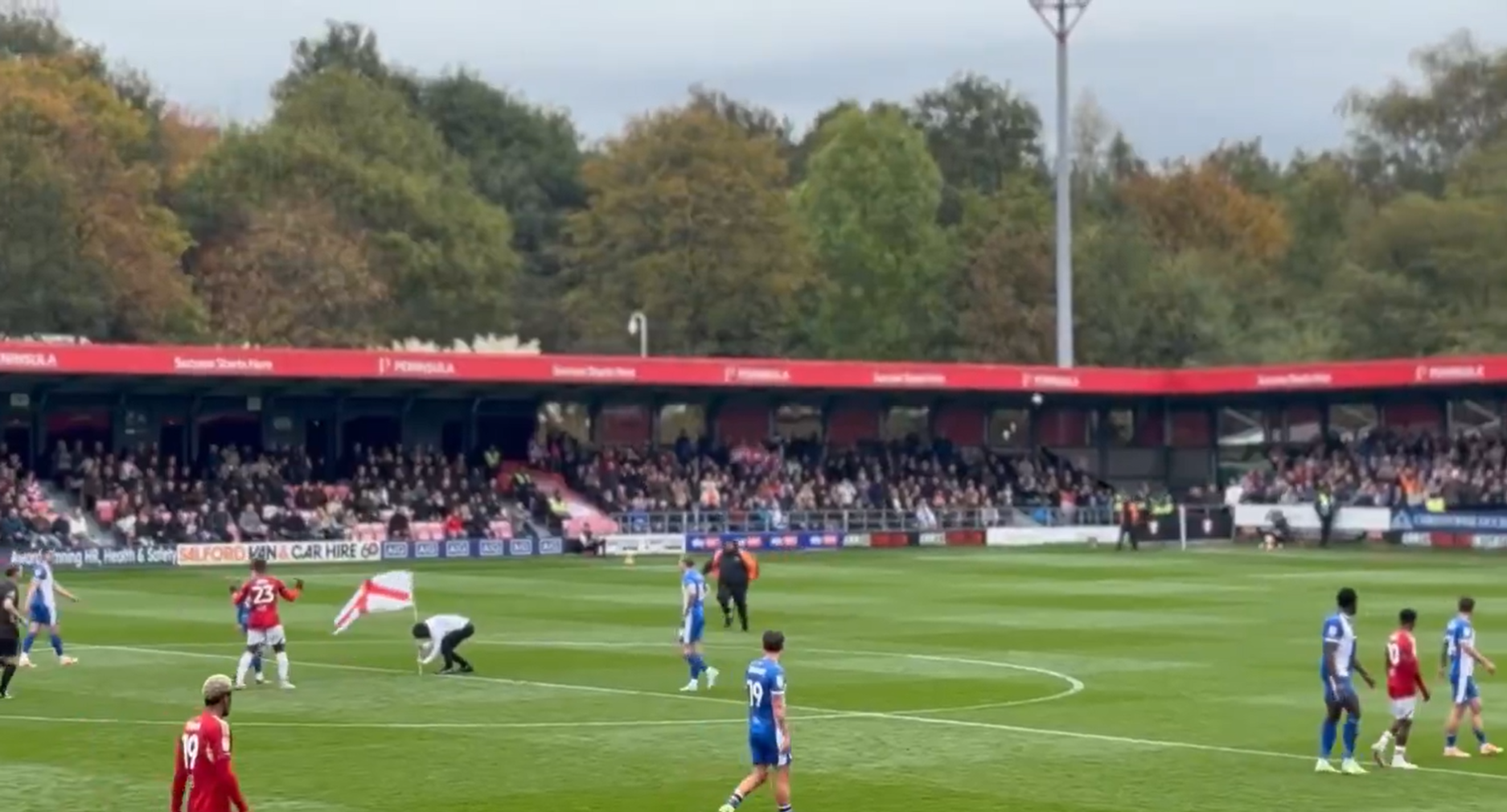 Pitch invaders plant an England flag in the middle of the pitch at Salford City