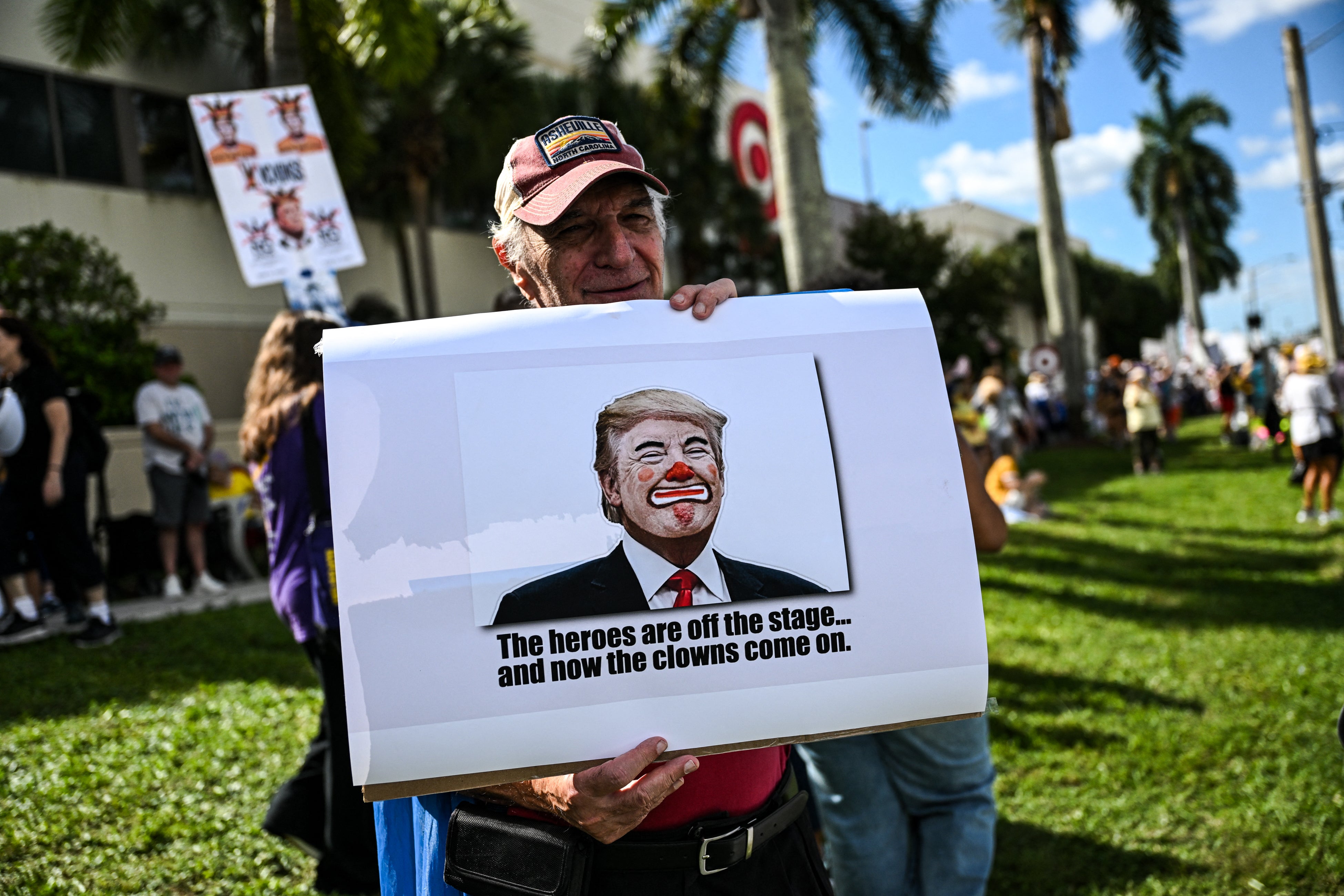 Protester holds up a sign that reads: ‘The heroes are off the stage... and now the clowns come in’