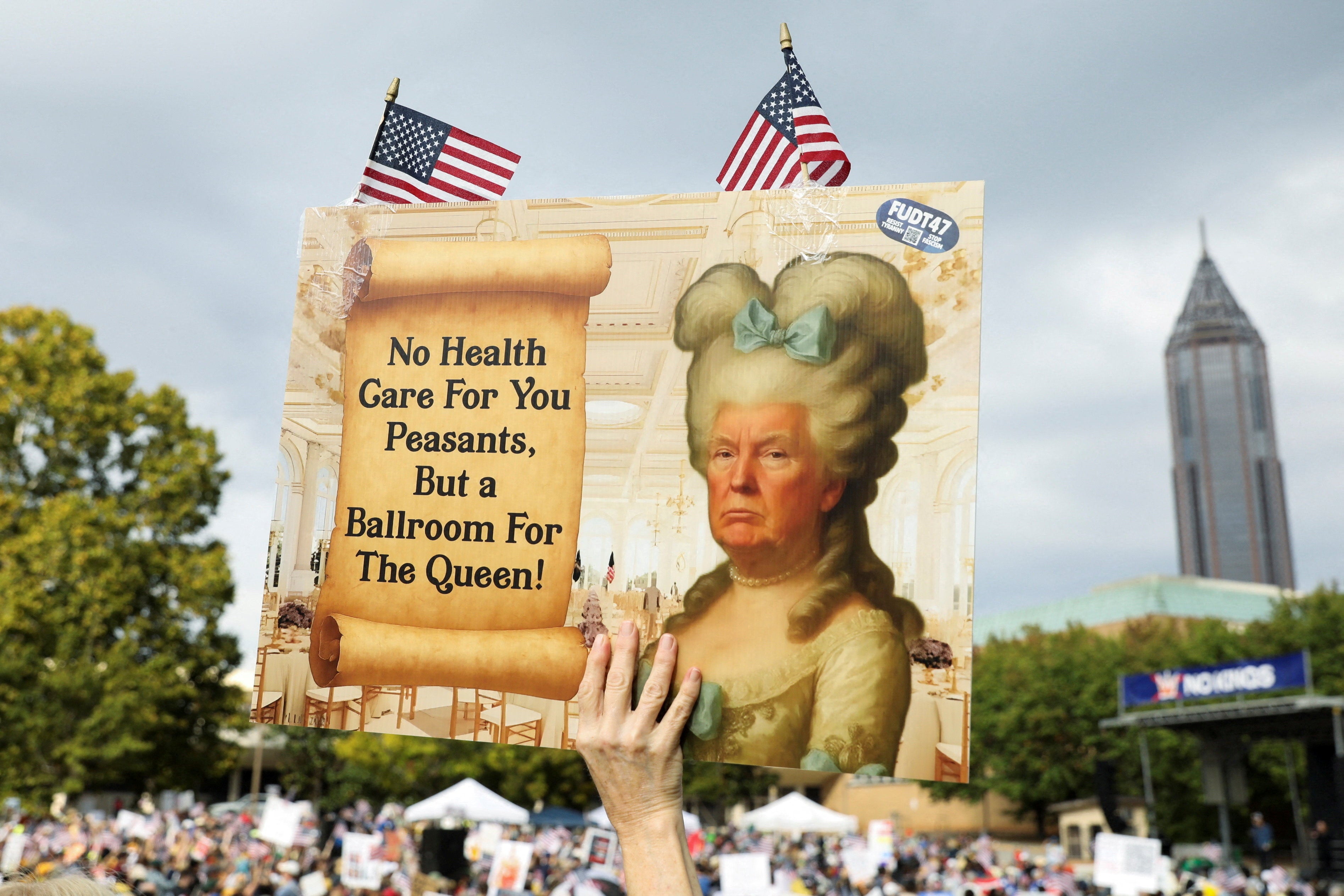 A person holds a placard with an image depicting Trump as Marie Antoinette at the Atlanta rally