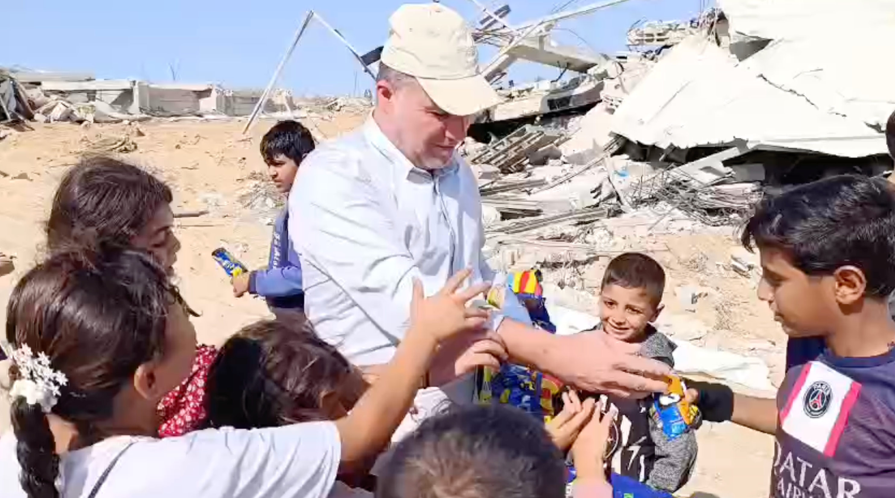 Hossam al-Astal hands out sweets to children east of Khan Younis behind Israel’s withdrawal line