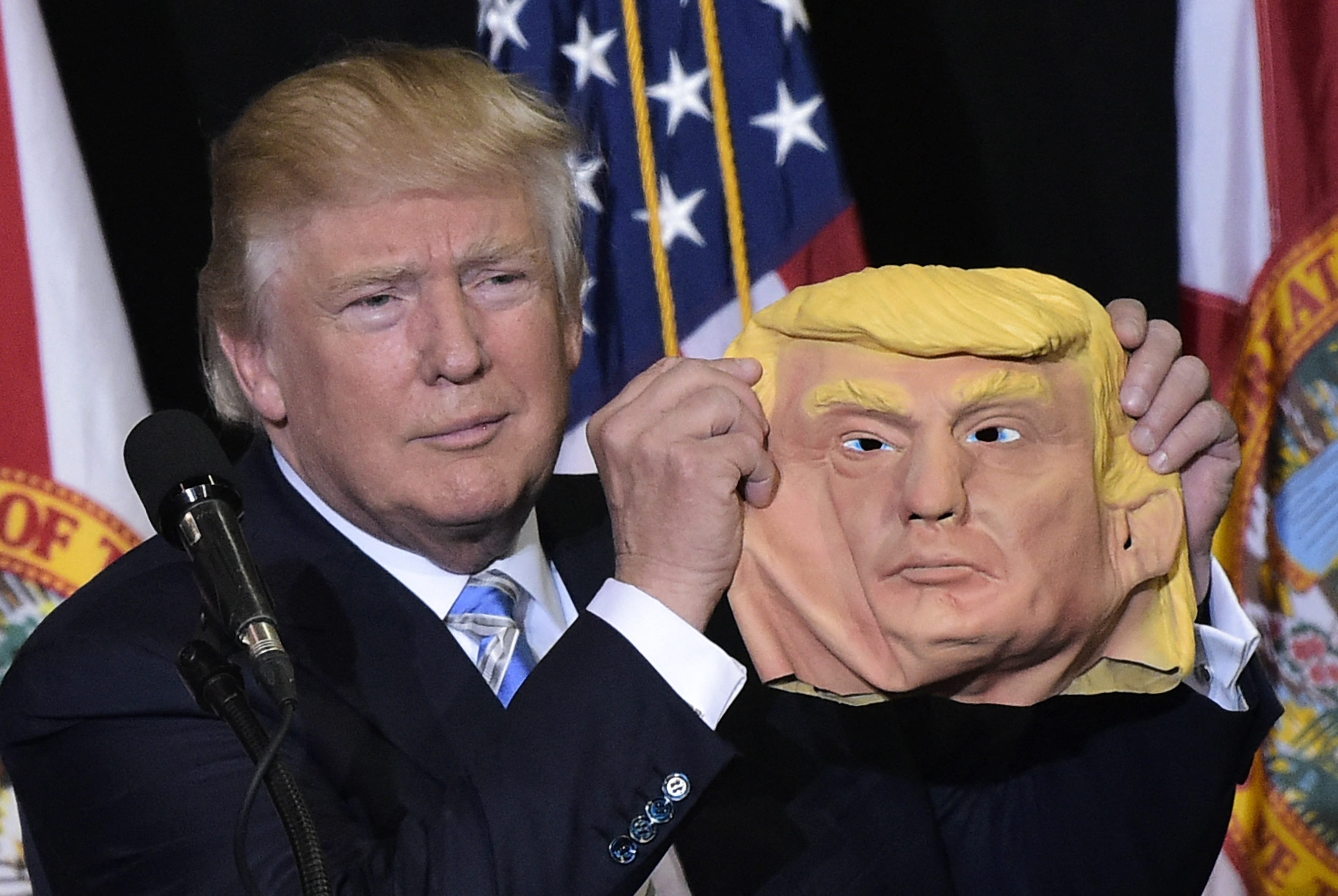 Donald Trump holds a mask of himself in 2016 at Florida rally