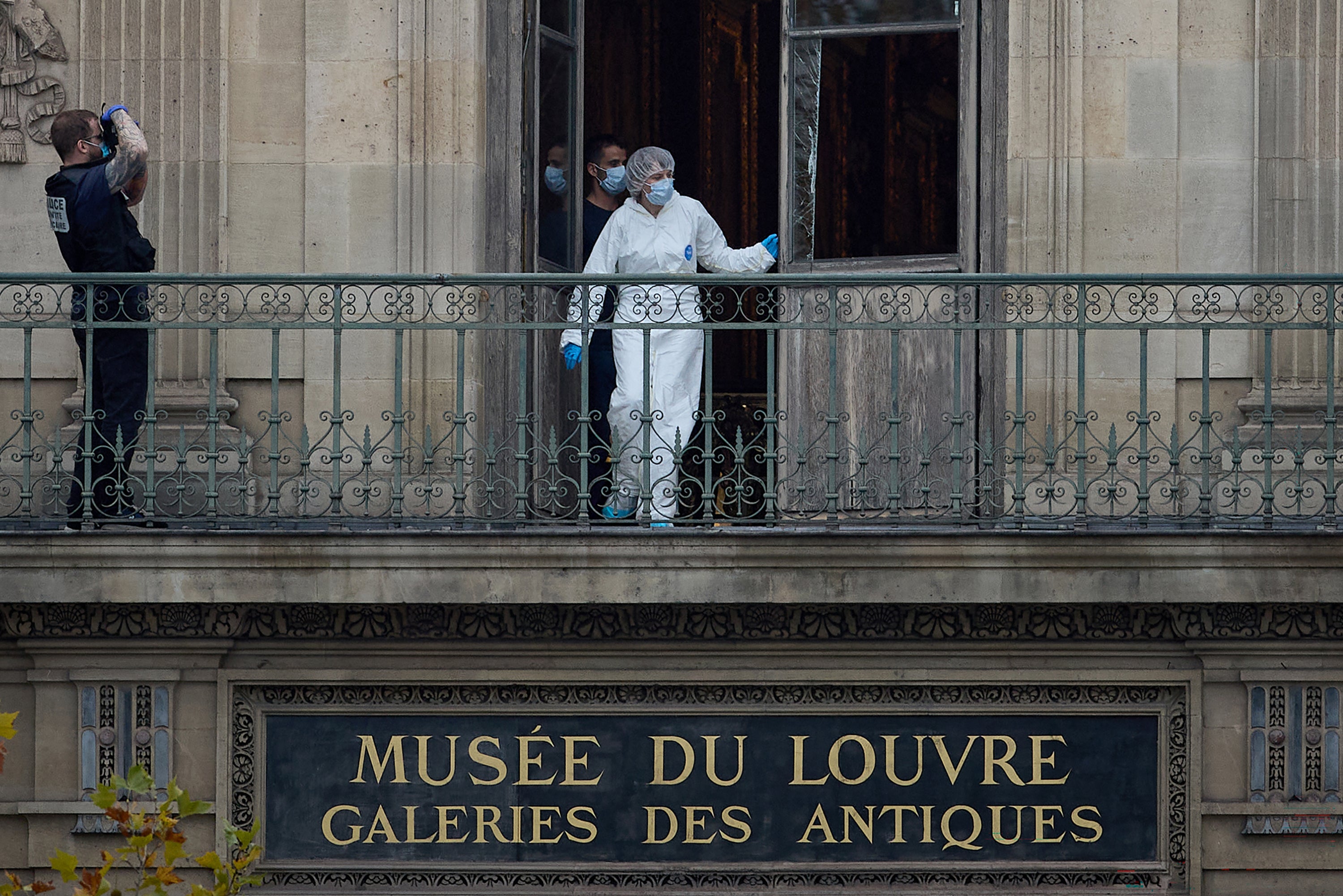 A forensics officer examines the window used by thieves to access the Louvre Museum