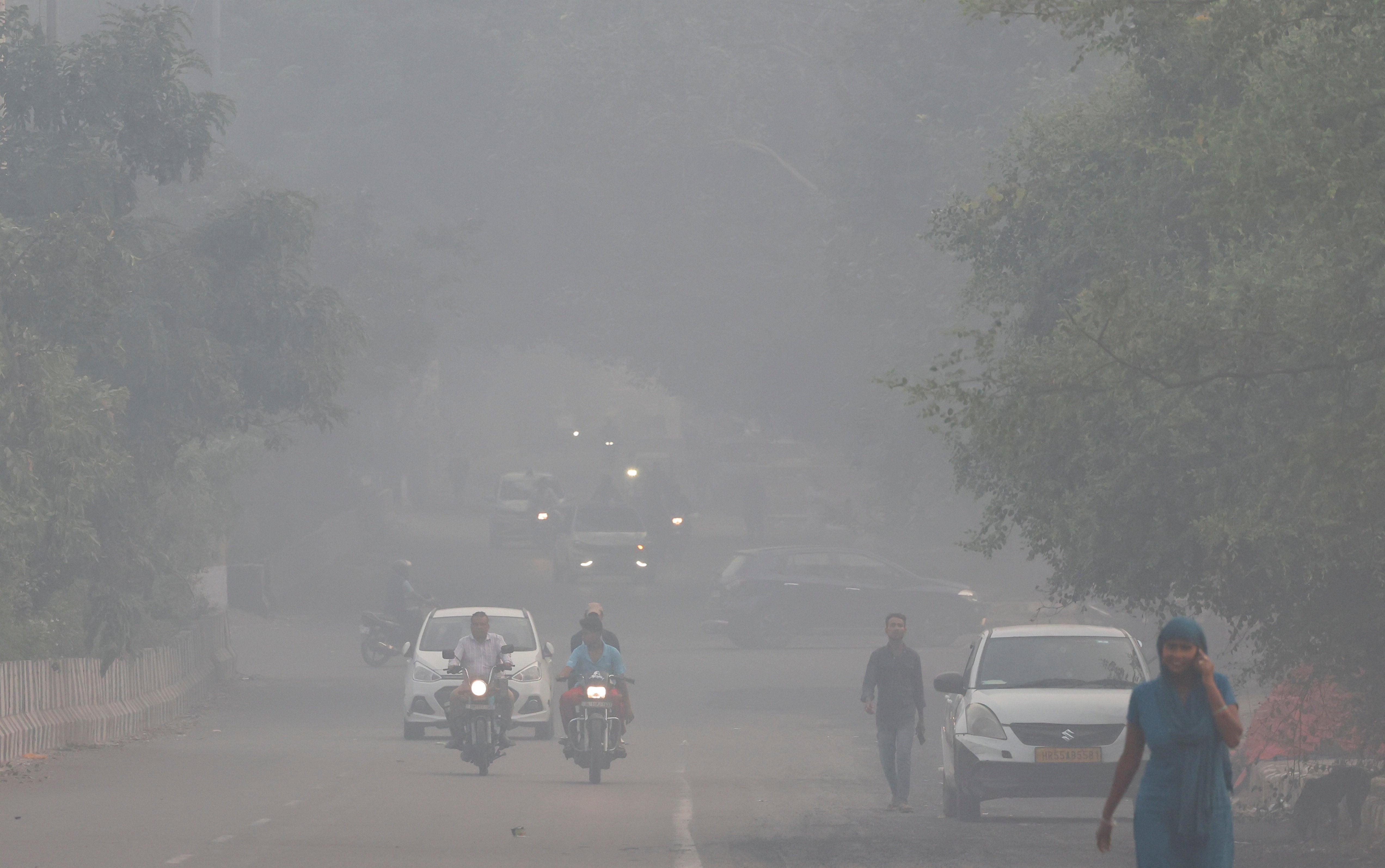 Vehicles move on a road shrouded in smog in New Delhi, 20 October 2025