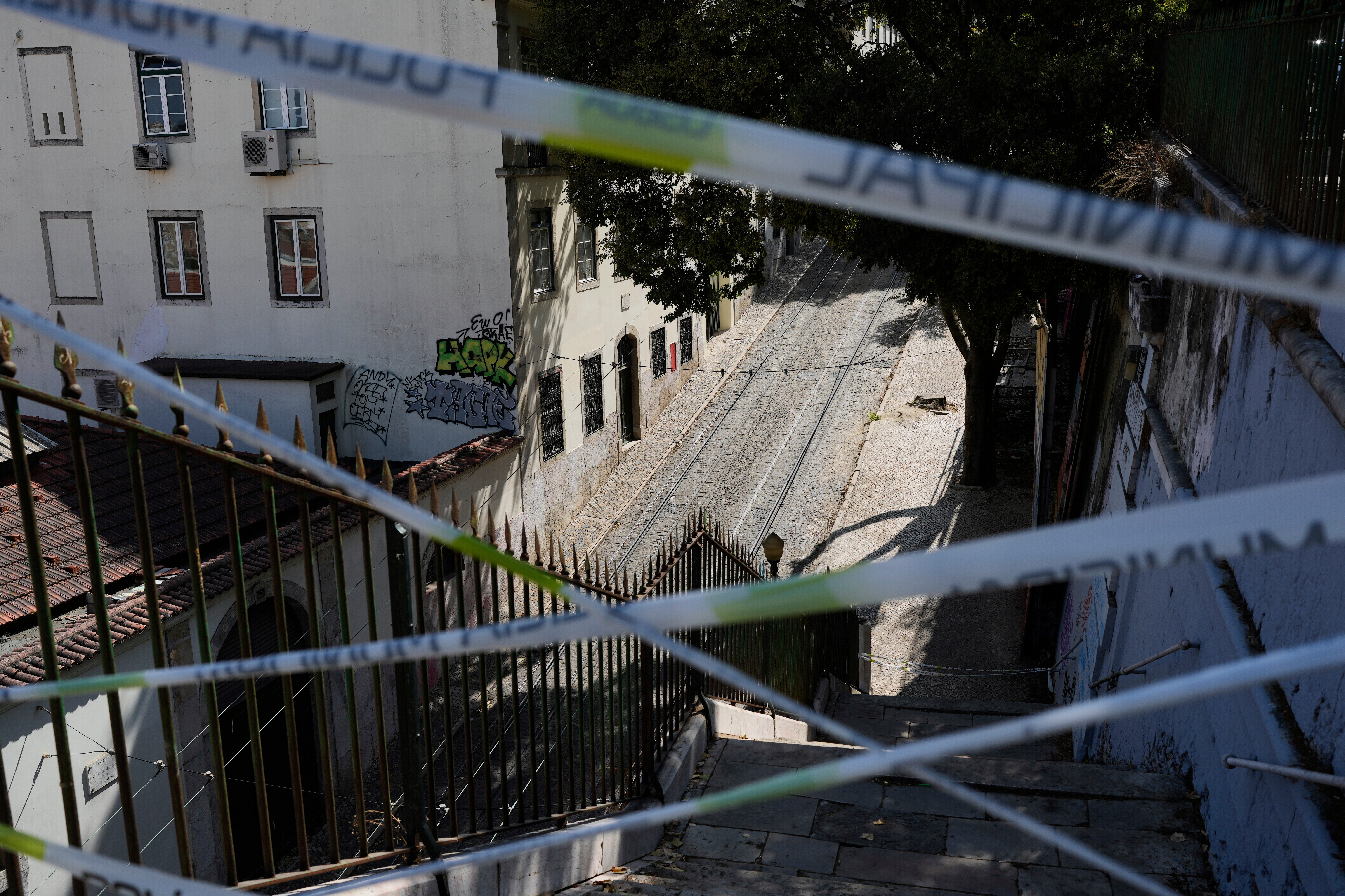Police tape cordons off the access to the tracks of the Gloria funicular, a tourist streetcar that derailed and crashed, in Lisbon on 5 September 2025.