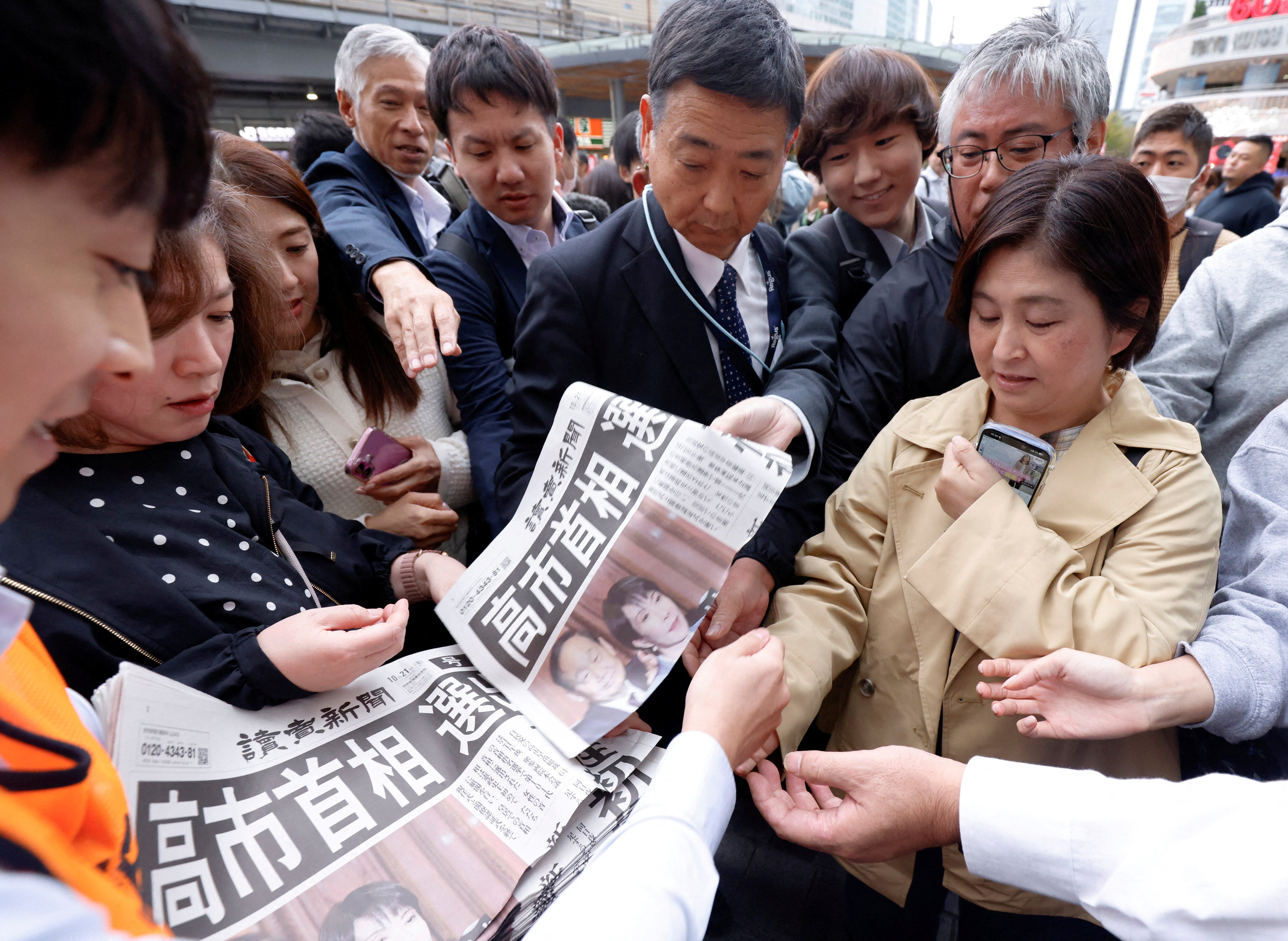 People receive extra editions of a newspaper reporting that the leader of Japan's ruling Liberal Democratic Party (LDP), Sanae Takaichi, has become the country's new prime minister, in Tokyo, Japan, 21 October 2025