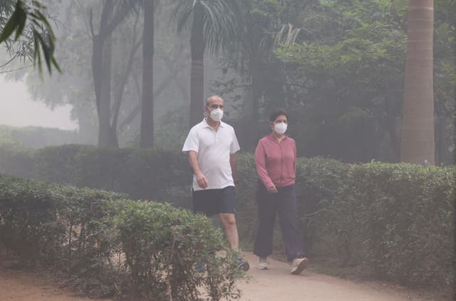 <p>People walk through smog the day after Diwali in New Delhi on 21 October 2025</p>