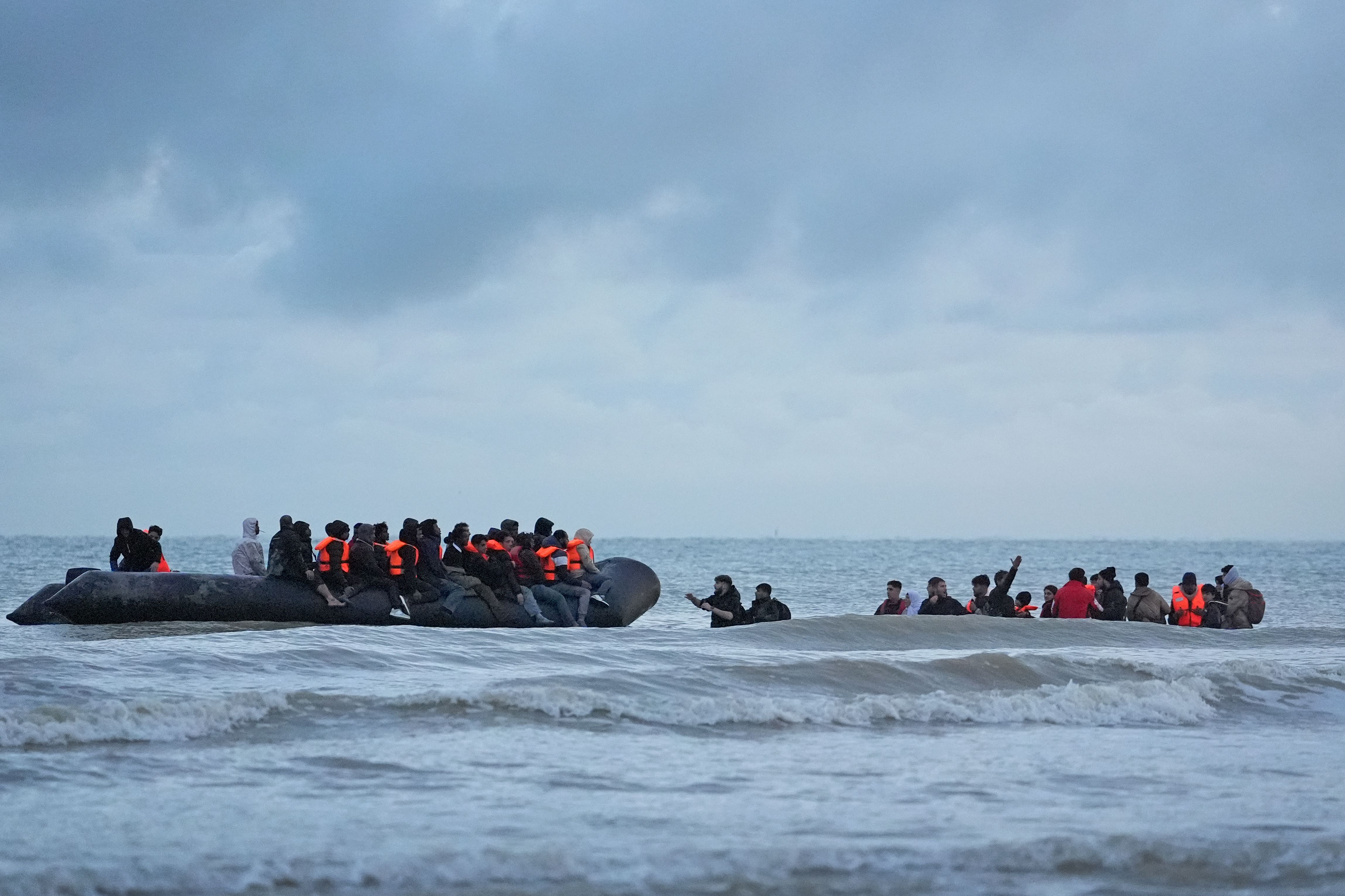 People thought to be migrants wade through the sea to board a small boat in Gravelines, France (Gareth Fuller/PA)