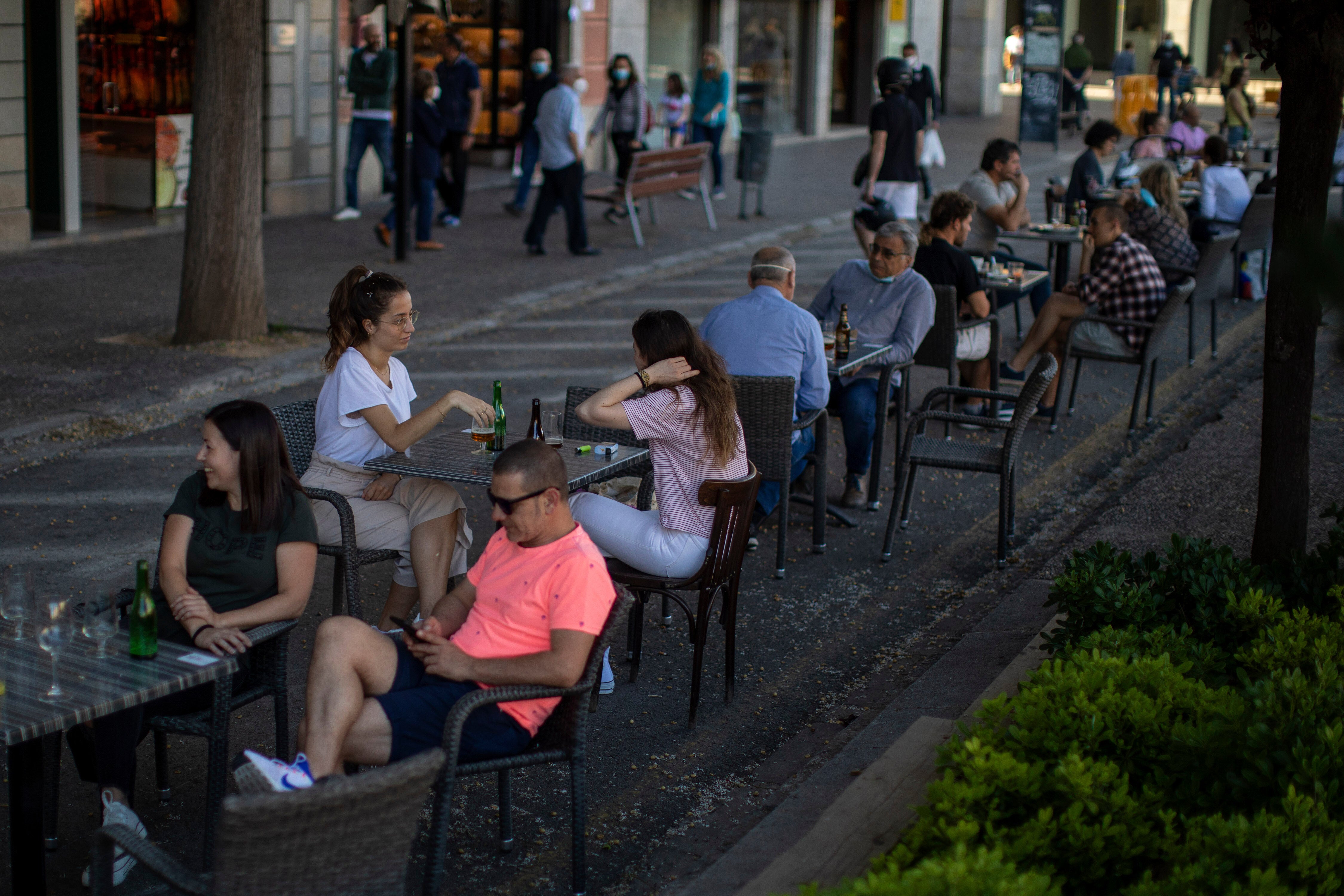 Customers sit at tables and chairs in Girona, Spain
