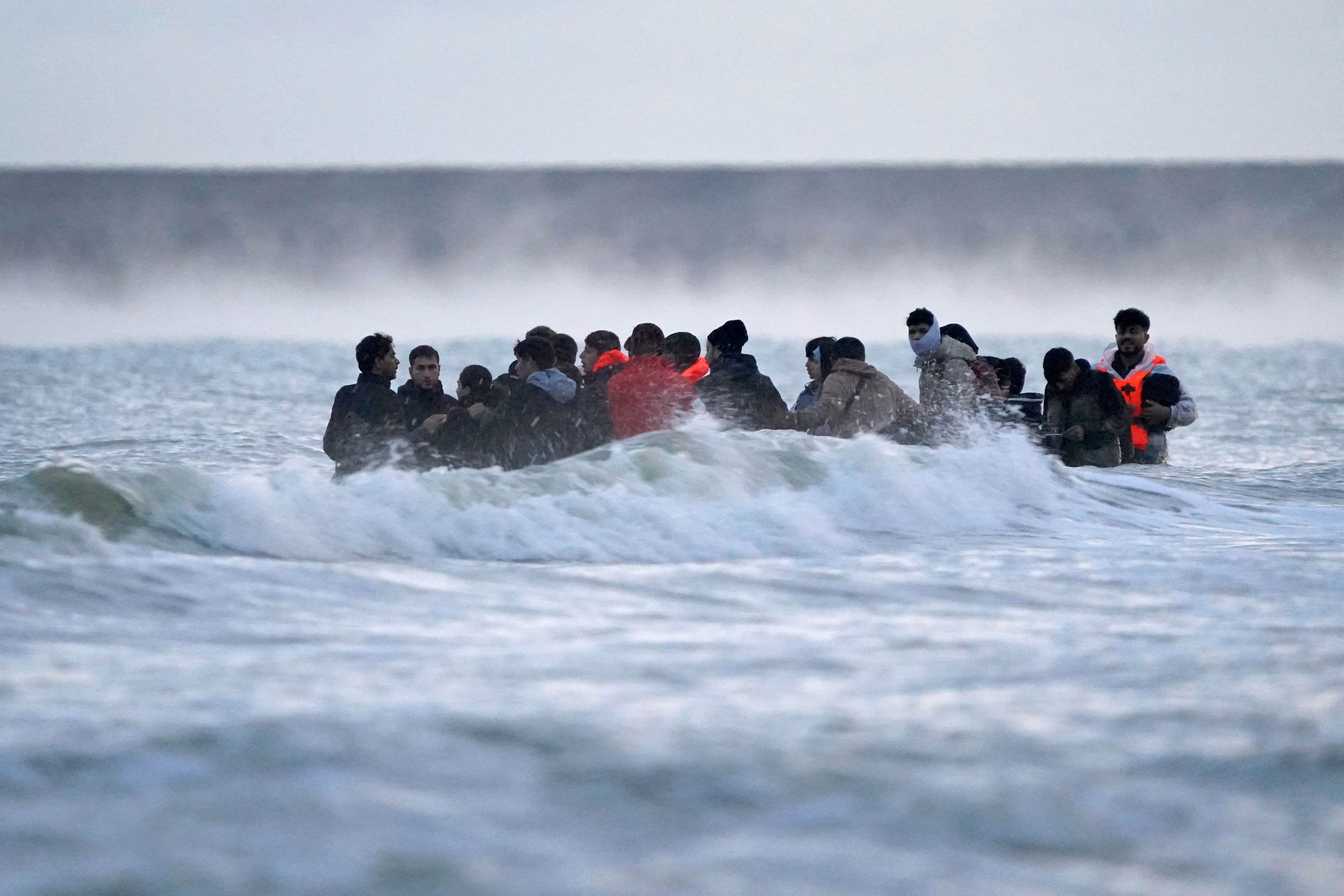 People thought to be migrants wait in the sea to board a small boat in Gravelines, France (Gareth Fuller/PA)