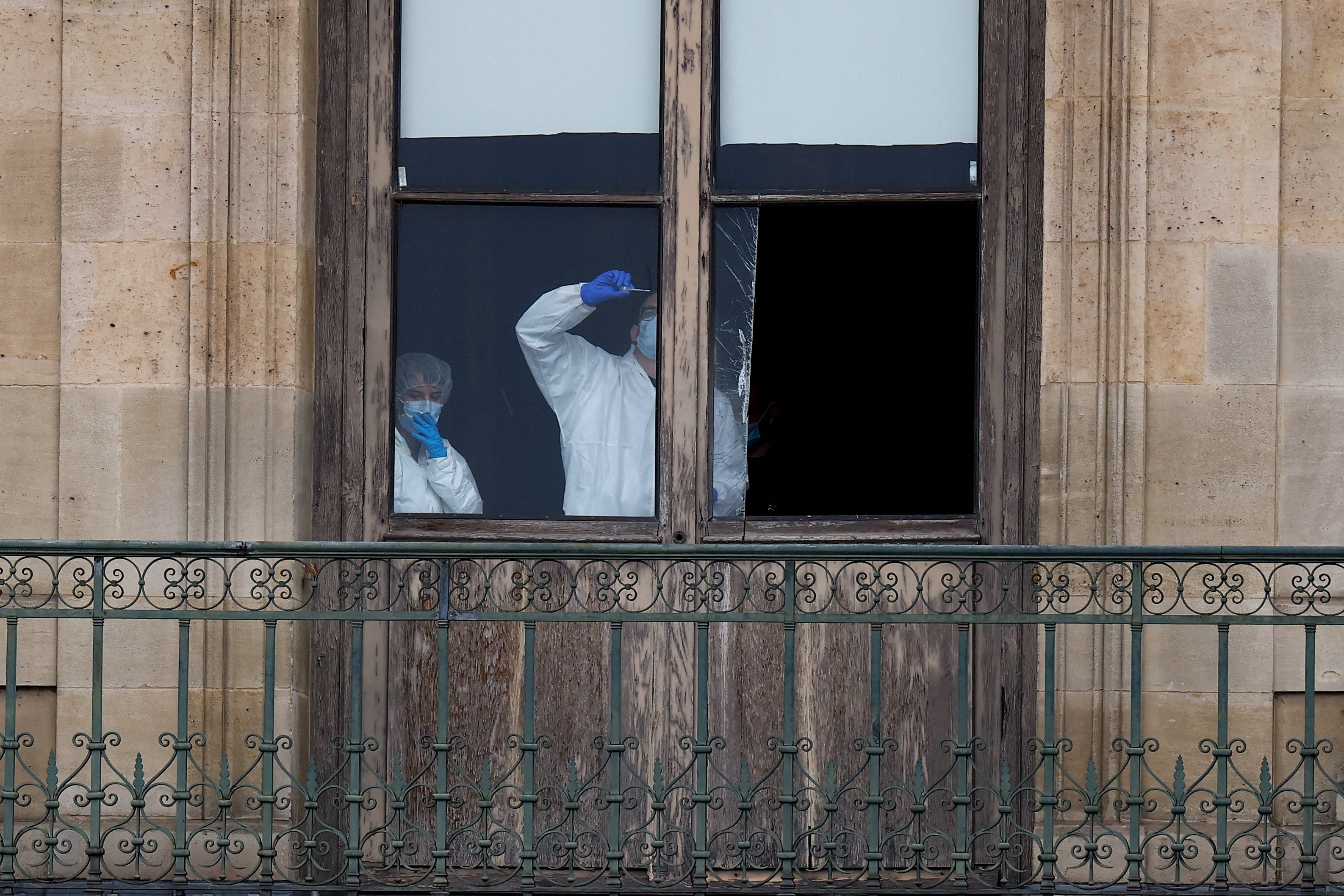 Members of a forensic team inspect a window believed to have been used in the Louvre heist