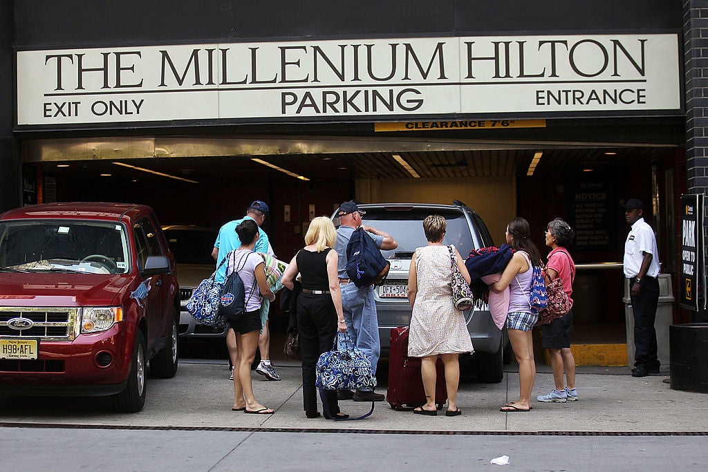 People prepare to check in to the Millenium Hilton hotel in New York City. The hotel giant cut its forecast for 2025 room revenue growth, suggesting that the current weaker demand for vacations within the U.S. will likely persist.