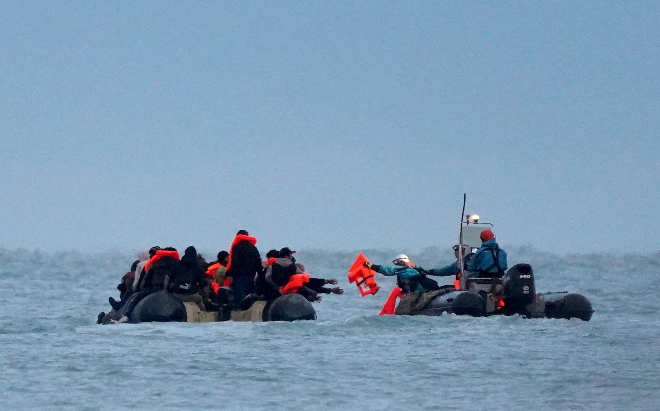 Migrants are given life jackets by the French authorities as they leave the beach onboard a small boat in Gravelines
