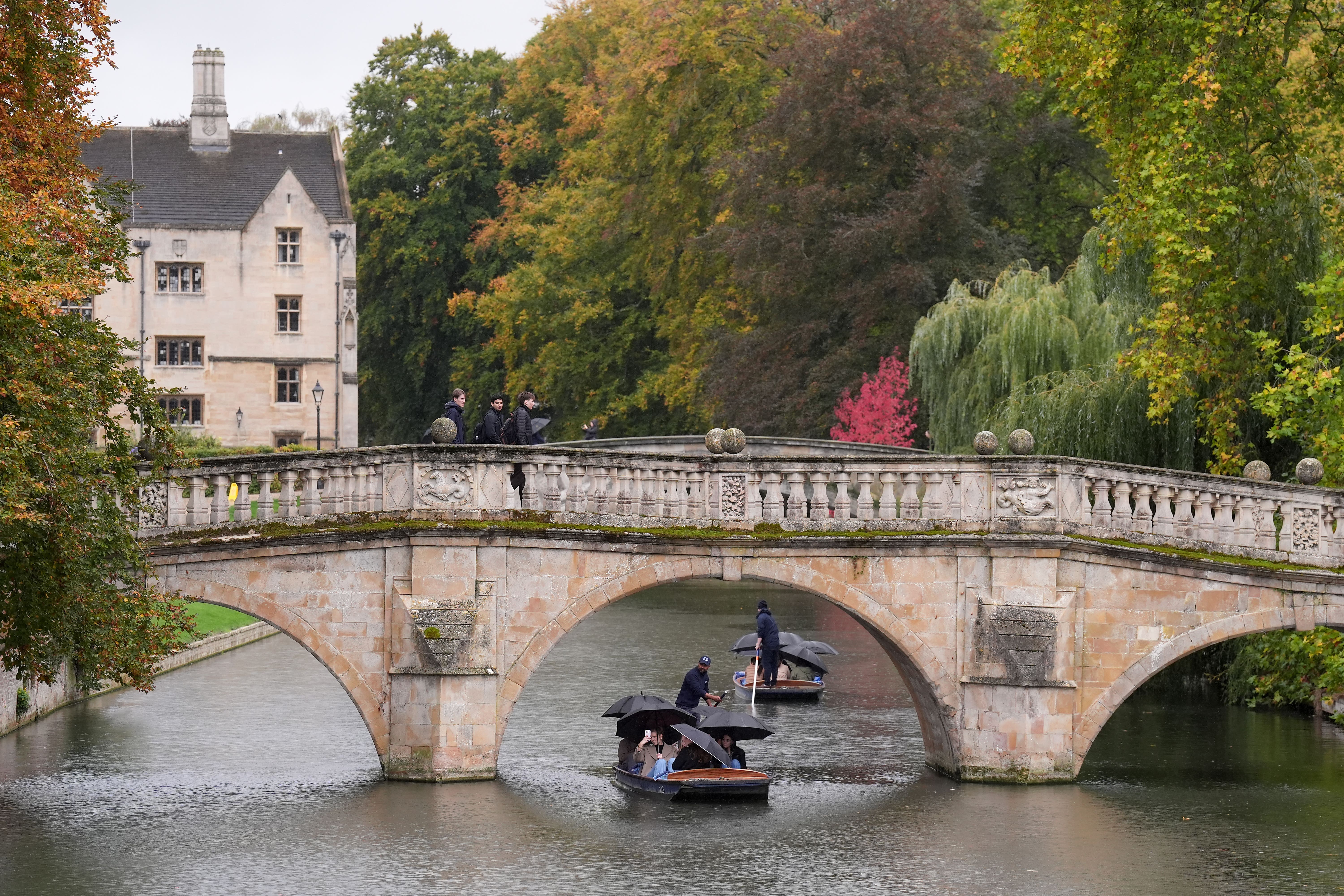 People shelter from the rain under umbrellas as they punt along the River Cam in Cambridge (Joe Giddens/PA)