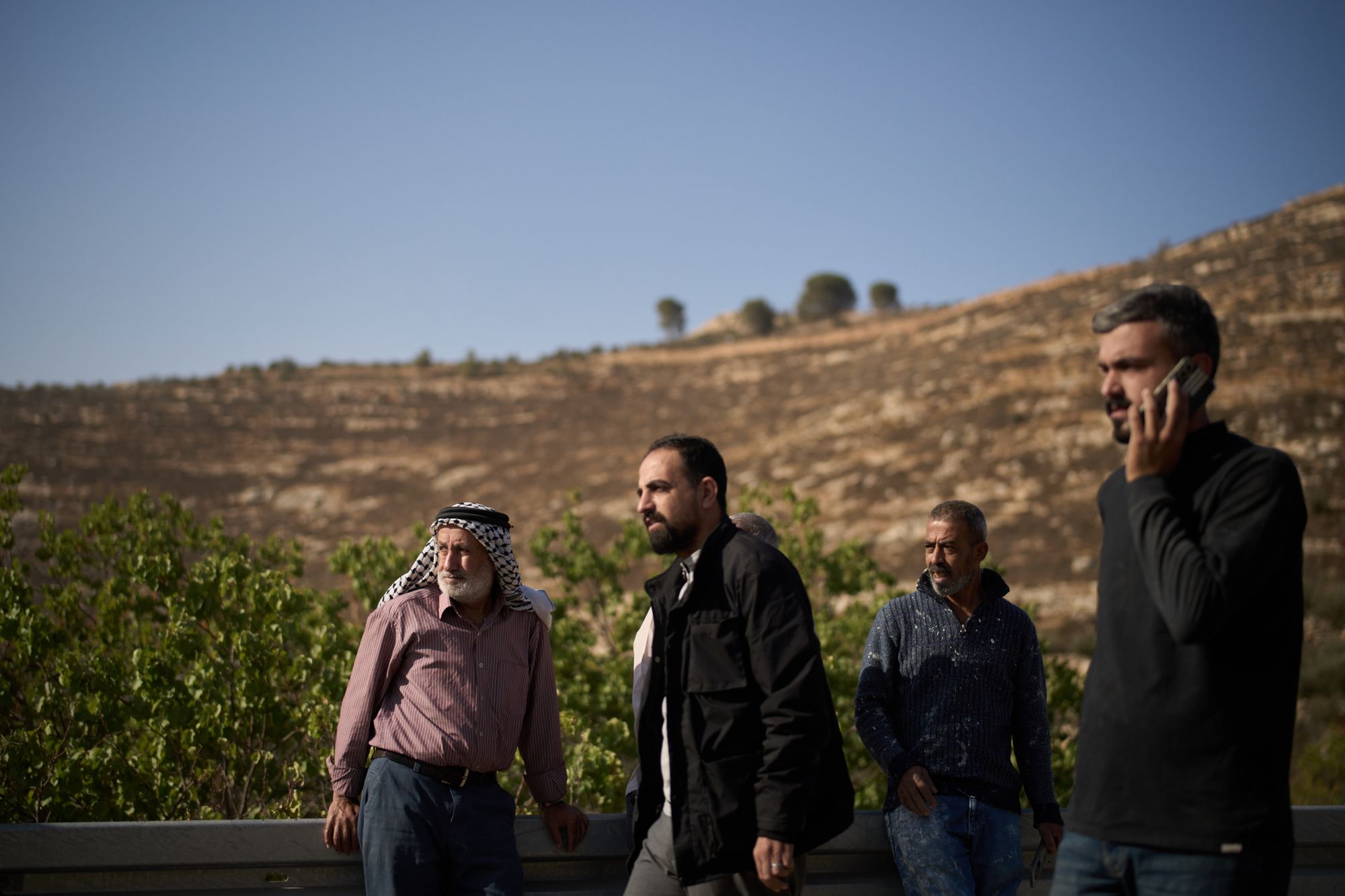 Palestinians on a road side after Israeli soldiers blocked access to an area for harvesting olives in the West Bank village of Sa'ir, near Hebron