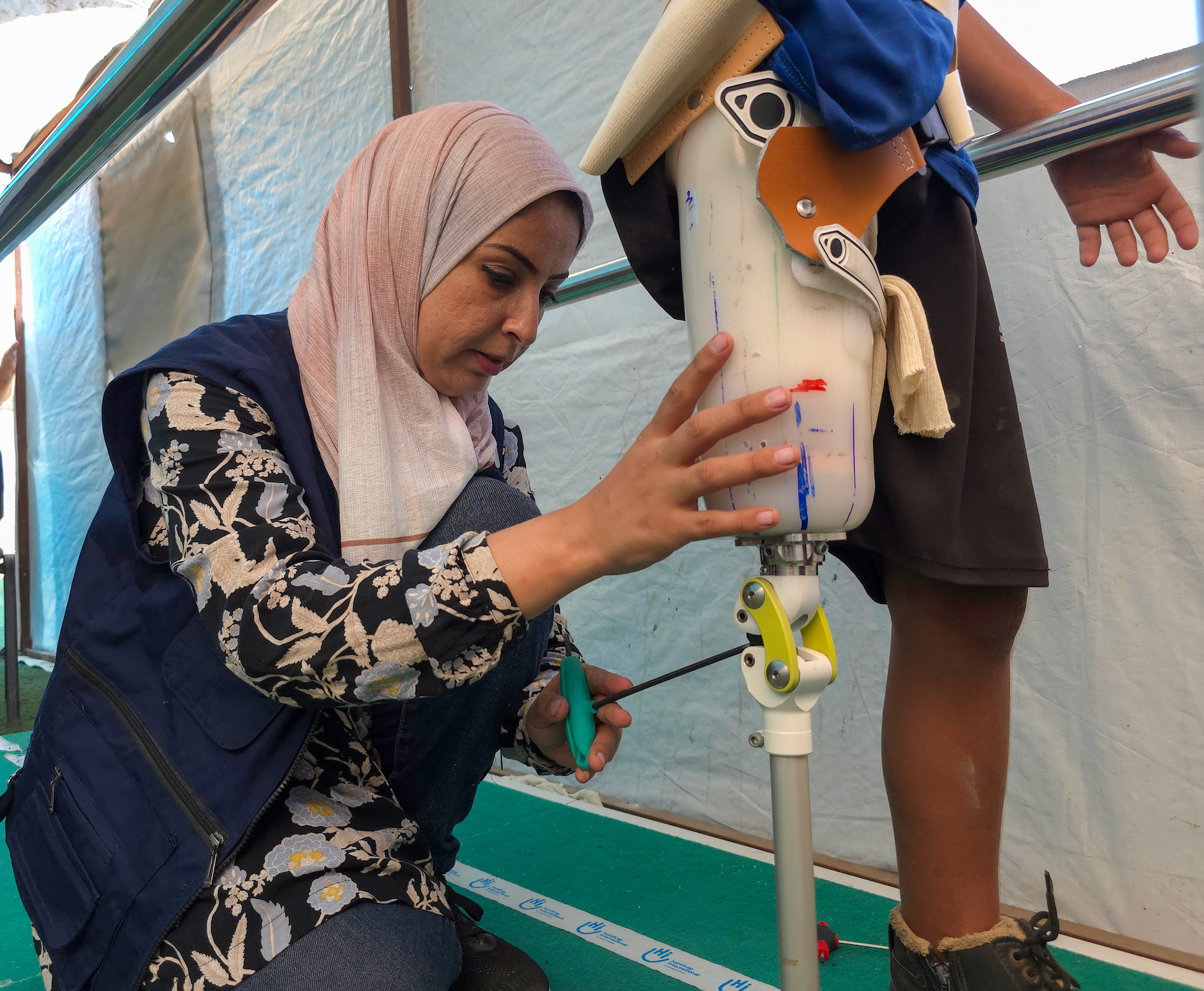 <p>Heba helping Mohammed, a 10-year-old boy who lost his leg</p>