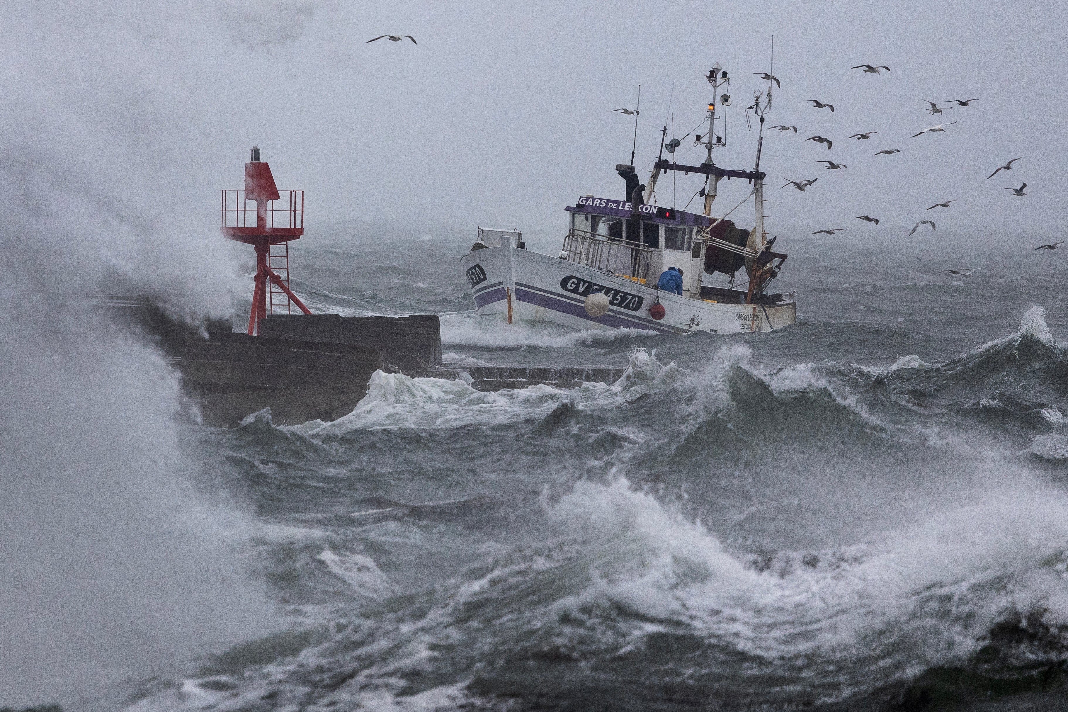 A fishing boat arrives at the port of Plobannalec-Lesconil, in western France, on Wednesday as huge waves and strong winds hit the area