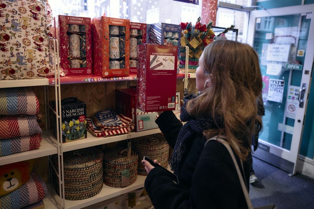 A customer browses Christmas crackers inside an Oxfam charity shop in London – shop revenues are down by two thirds over the past three years