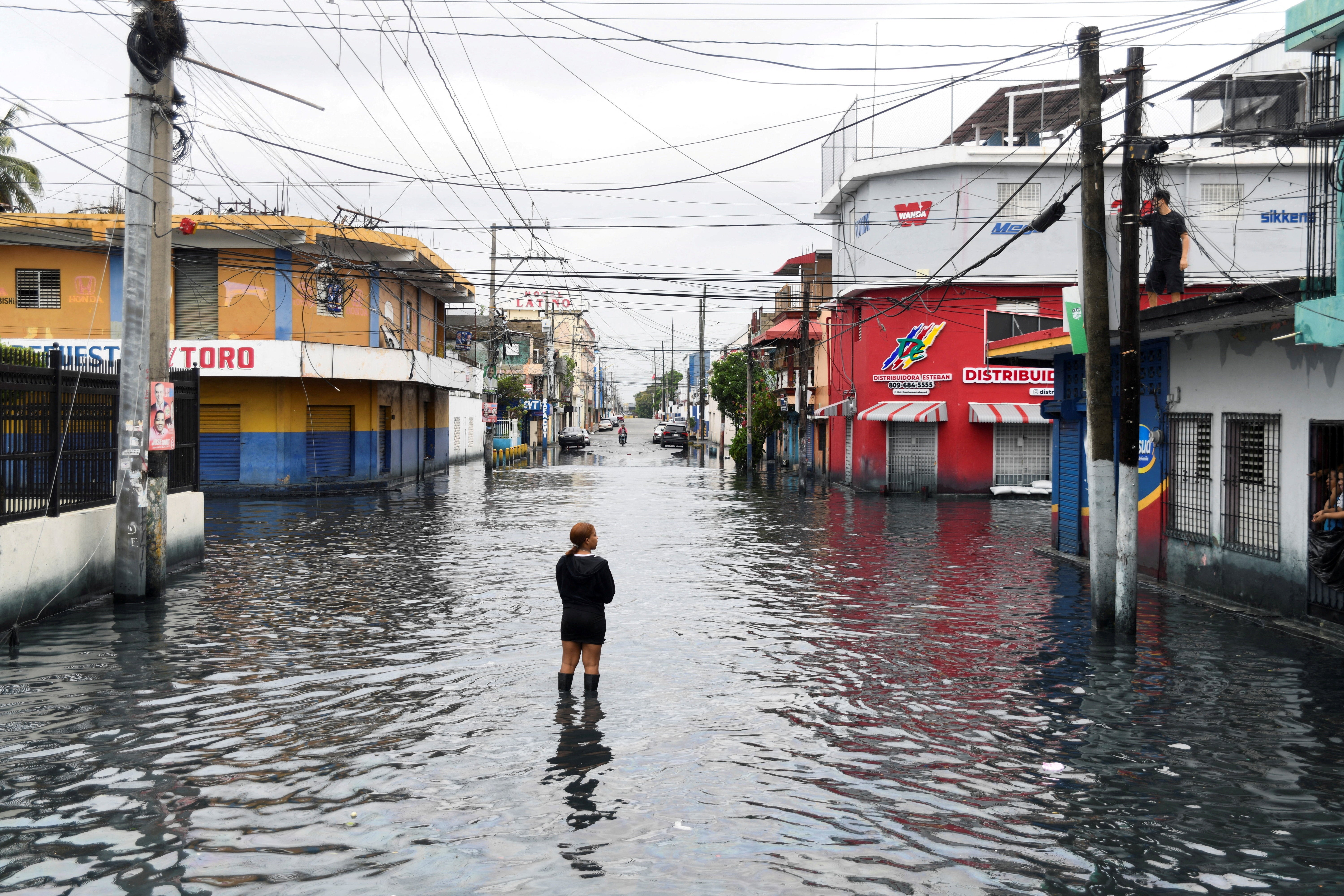 A woman is standing on a street flooded by rains caused by Tropical Storm Melissa, in Santo Domingo, Dominican Republic