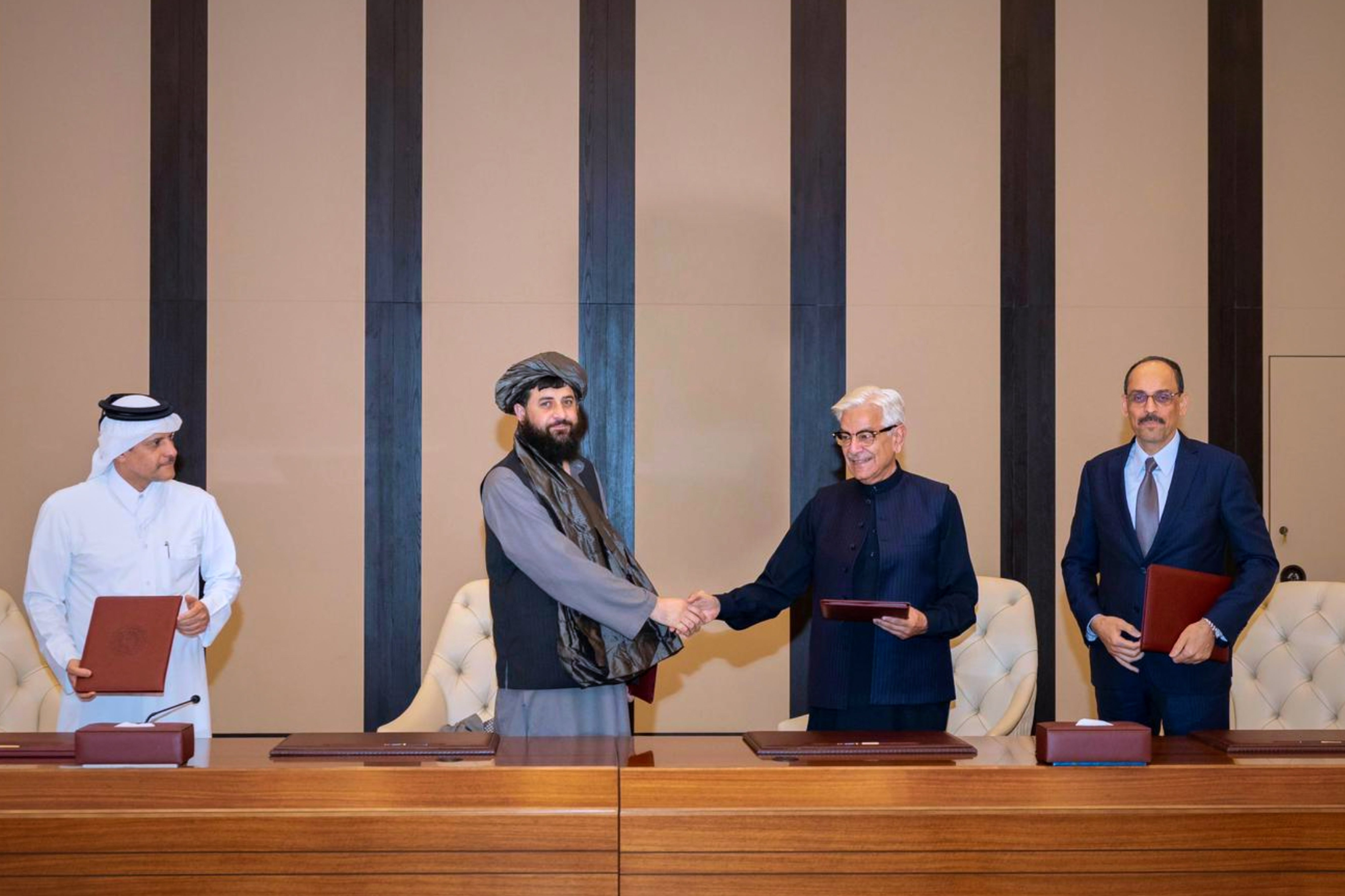 Pakistani Defence Minister Khawaja Asif, center right, and Afghan Defence Minister Mullah Muhammad Yaqoob shake hands after signing a ceasefire agreement in Doha, Qatar