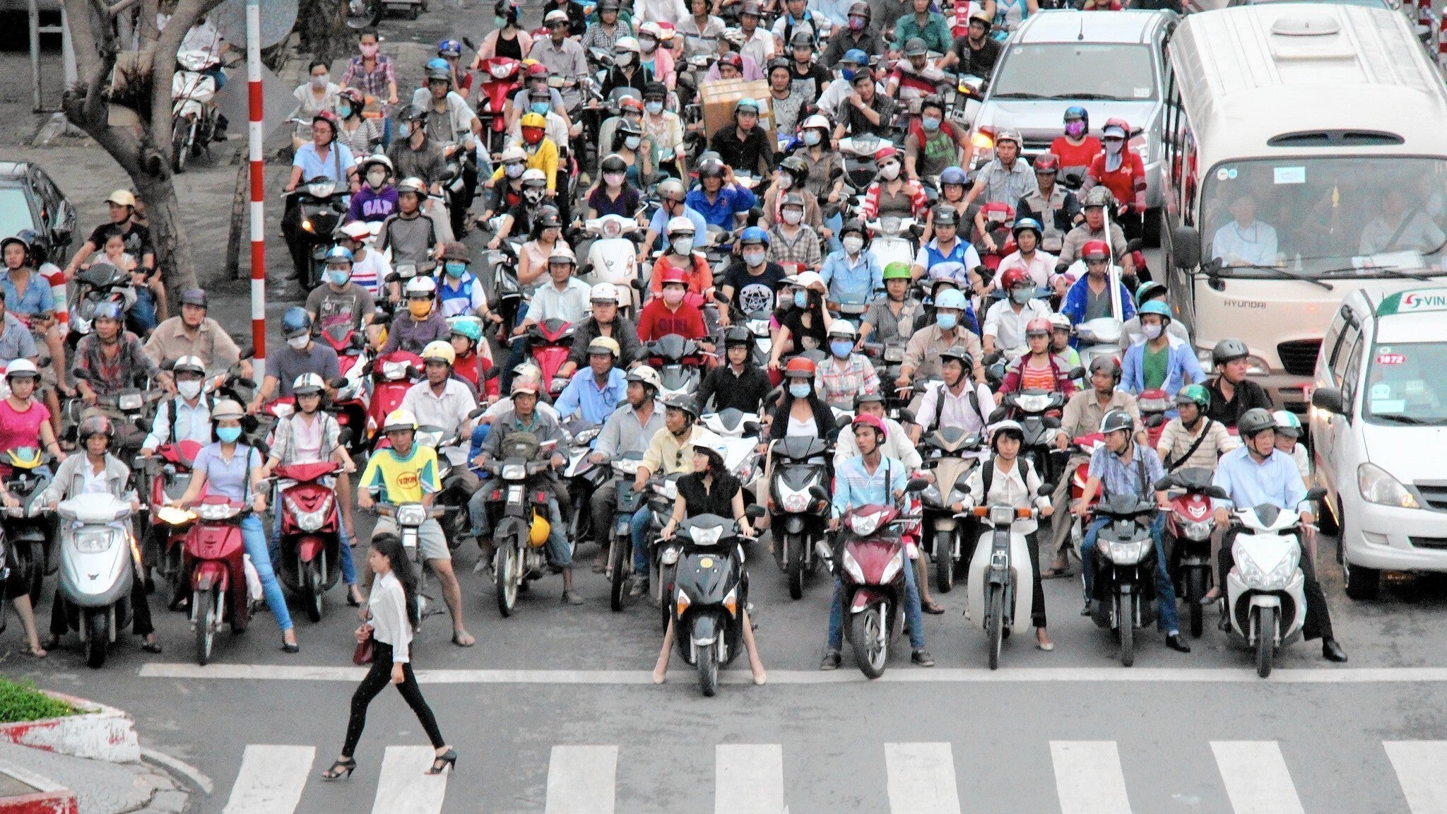 <p>A woman crosses the street in front of bikers in Ho Chi Minh City</p>