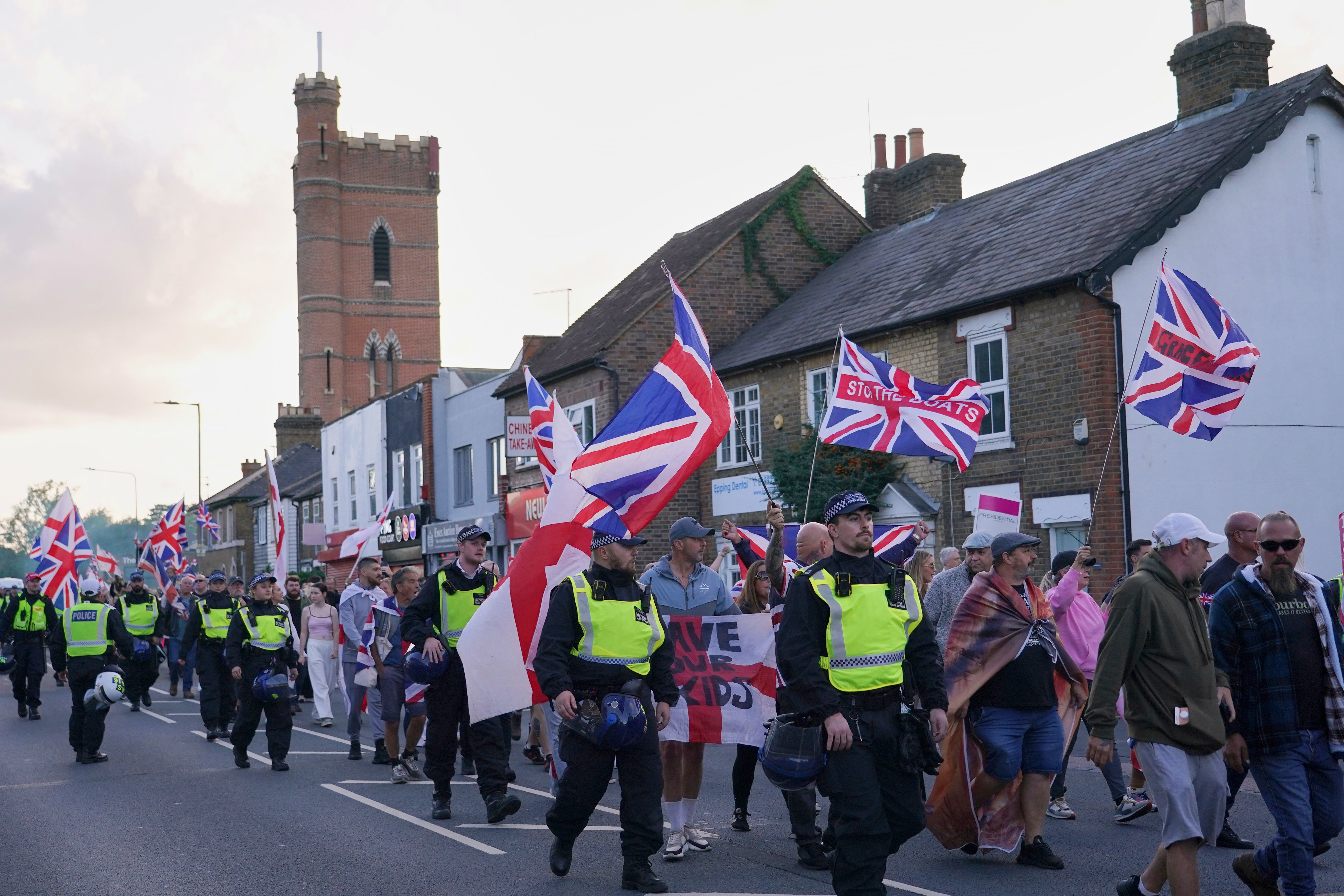 <p>Police officers escort protesters near the Bell Hotel in Epping in August after a temporary injunction that would have blocked asylum seekers from being housed at the hotel was overturned</p>