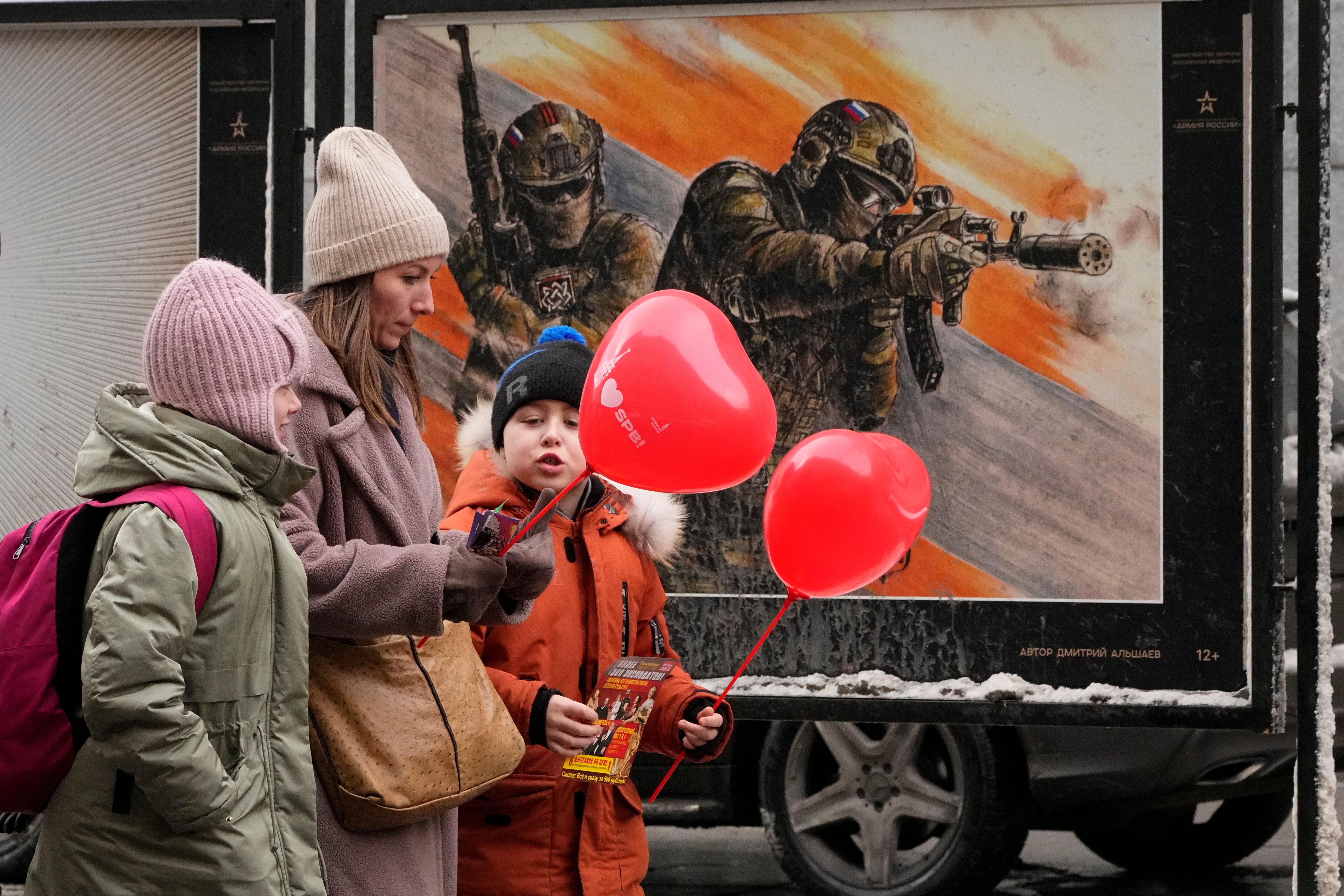 A woman and two children walk past military posters in St Petersburg earlier this year. The war in Ukraine is one of the factors thought to be behind Russia’s diminishing birth rate