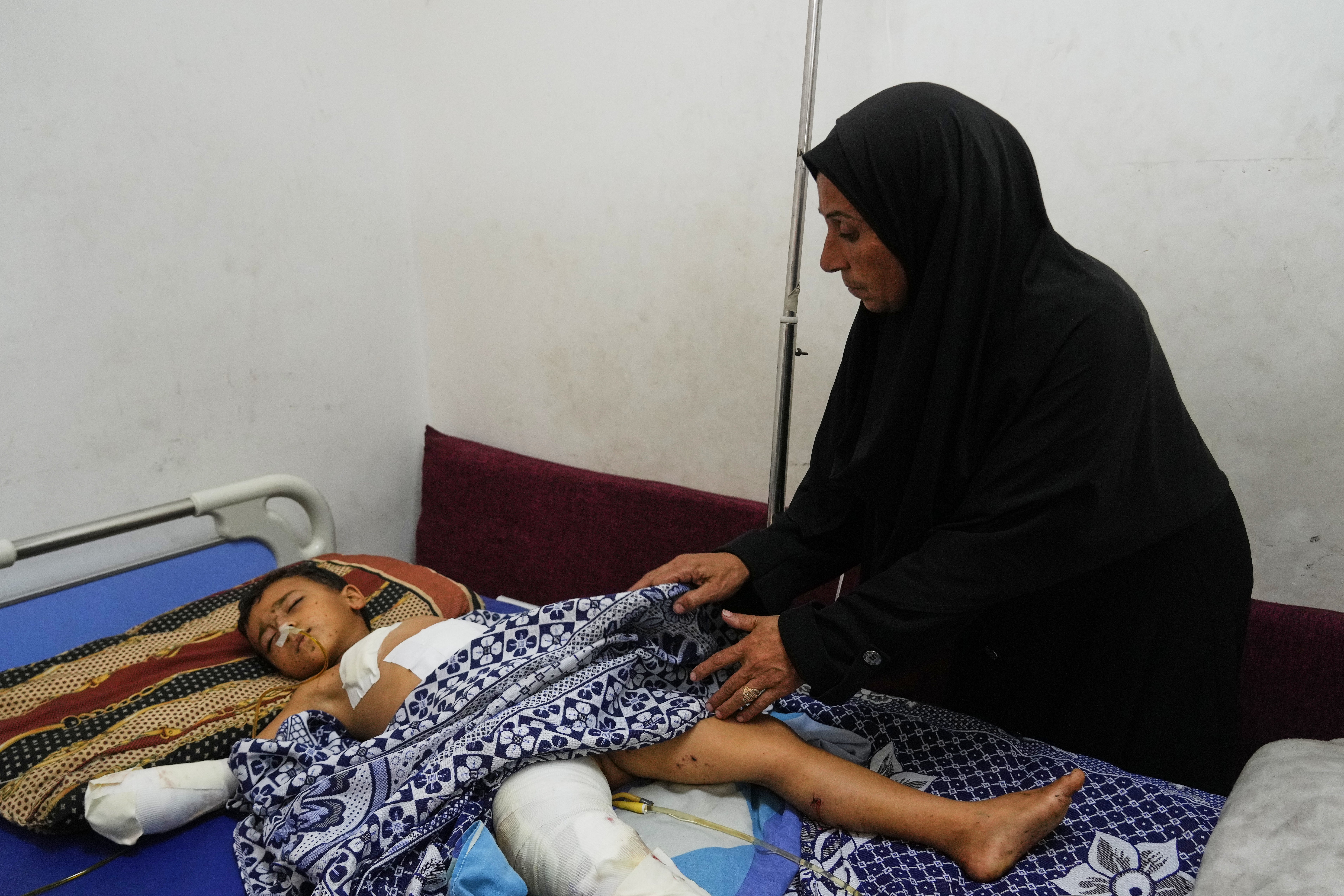 Hanan Shakshk cares her grandson Yahya Shorbasi, who was injured by an unexploded ordnance along with his six-year-old twin sister Nabila, at Shifa Hospital in Gaza City, Saturday, Oct. 25, 2025. (AP Photo/Abdel Kareem Hana)