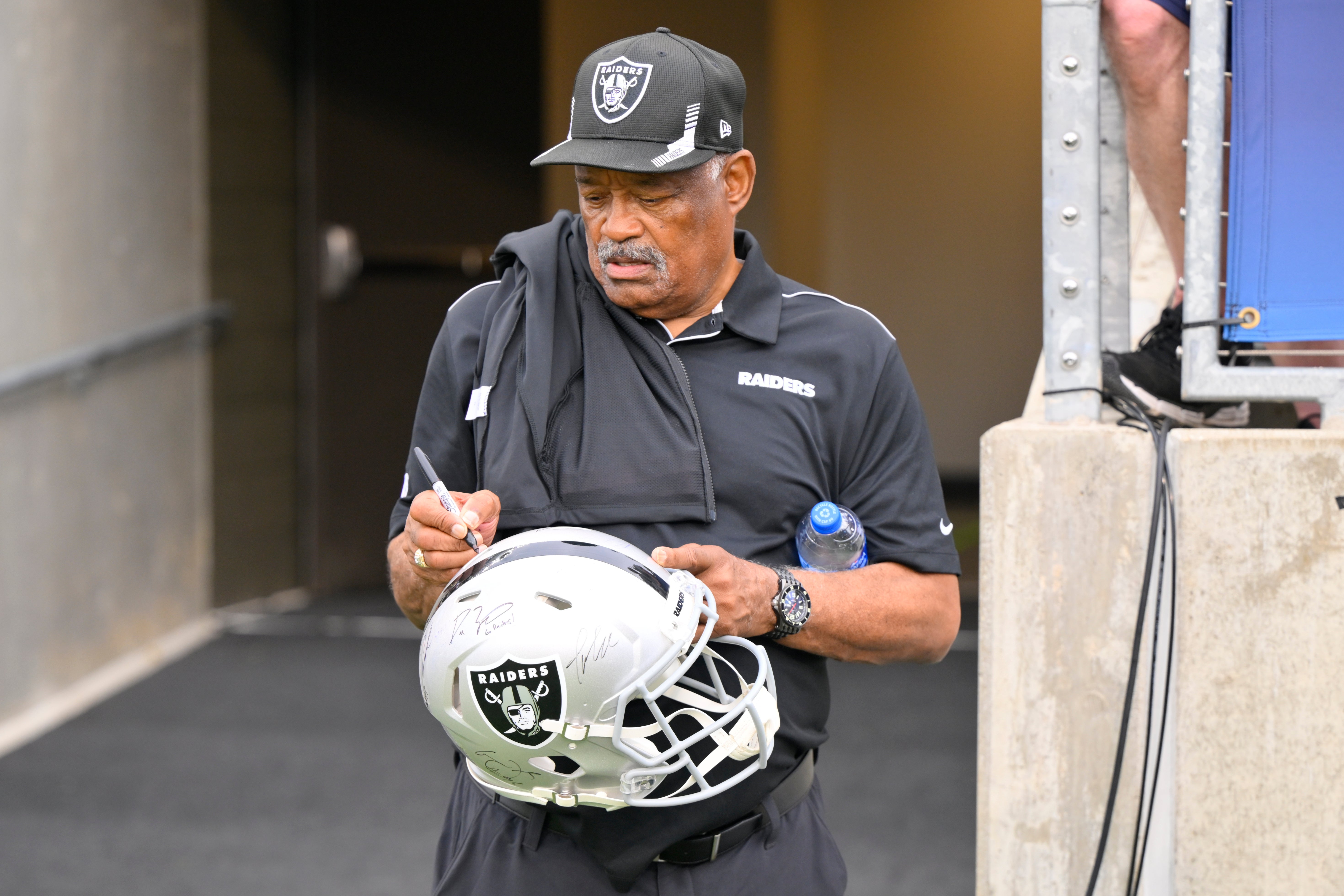 Former Oakland Raiders safety George Atkinson signs his autograph before the NFL football exhibition Hall of Fame Game between the Las Vegas Raiders and the Jacksonville Jaguars, Aug. 4, 2022, in Canton, Ohio. (AP Photo/David Richard, file)
