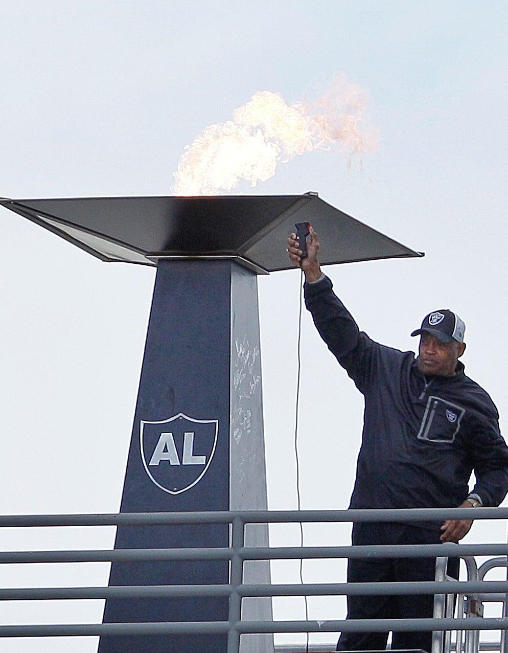 Former Oakland Raiders player George Atkinson waves after lighting a torch for former Raiders owner Al Davis before an NFL football game between the Oakland Raiders and the Jacksonville Jaguars in Oakland, Calif., Oct. 21, 2012. (AP Photo/Jeff Chiu, file)
