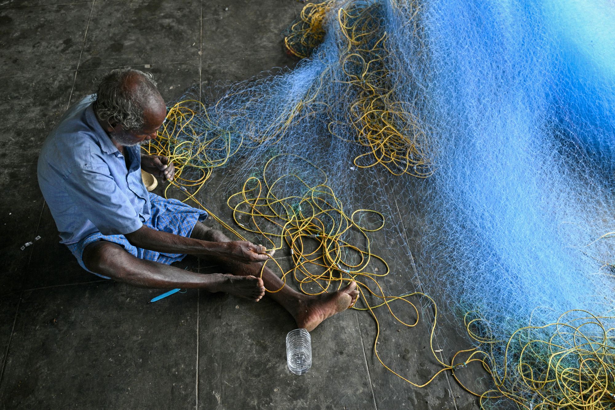 A fisherman repairs his net ahead of Cyclone Montha at the Marina beach in Chennai