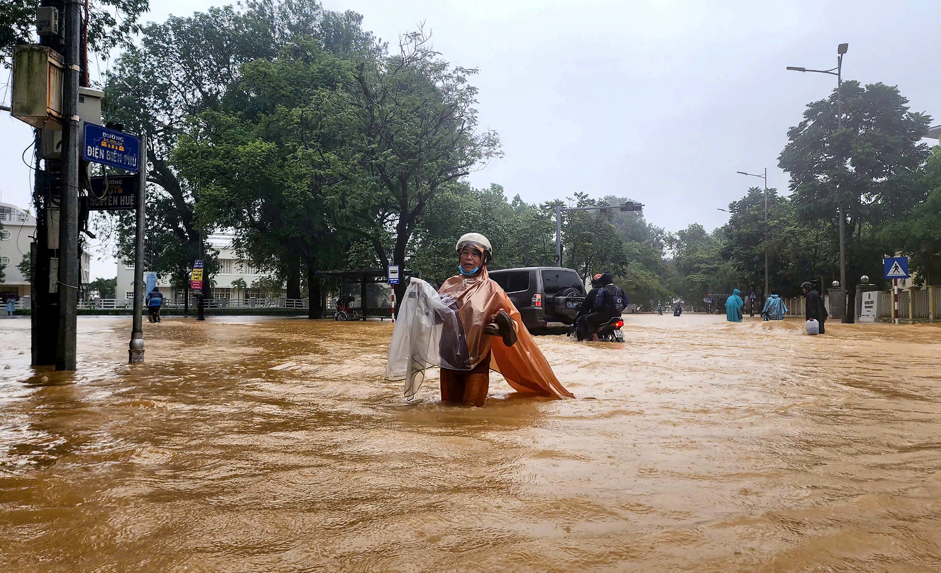 A woman wearing a raincoat wades through a flooded street in Hue.