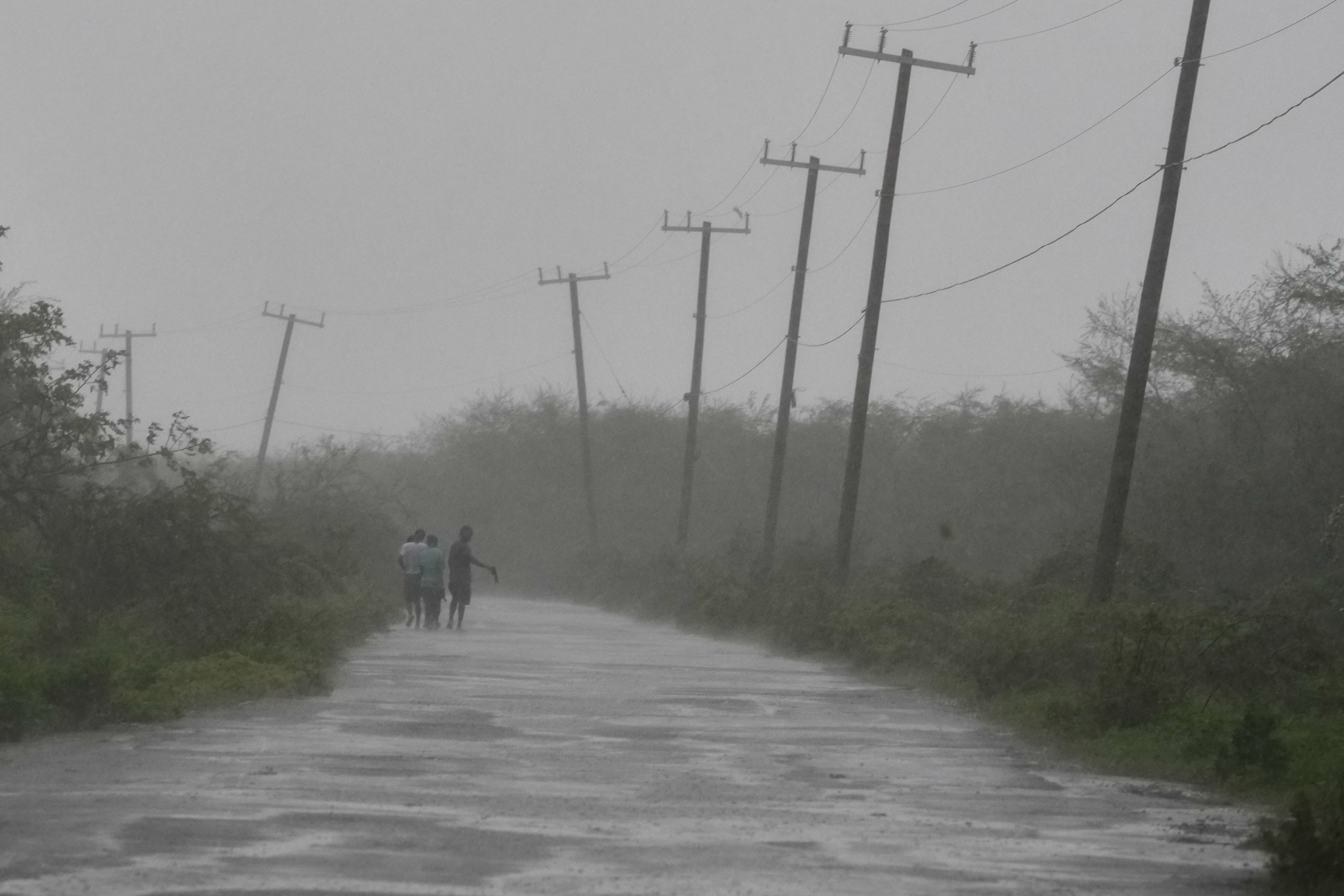 ‘The skies are impenetrably grey’: People walk down a road in Rocky Point, Jamaica