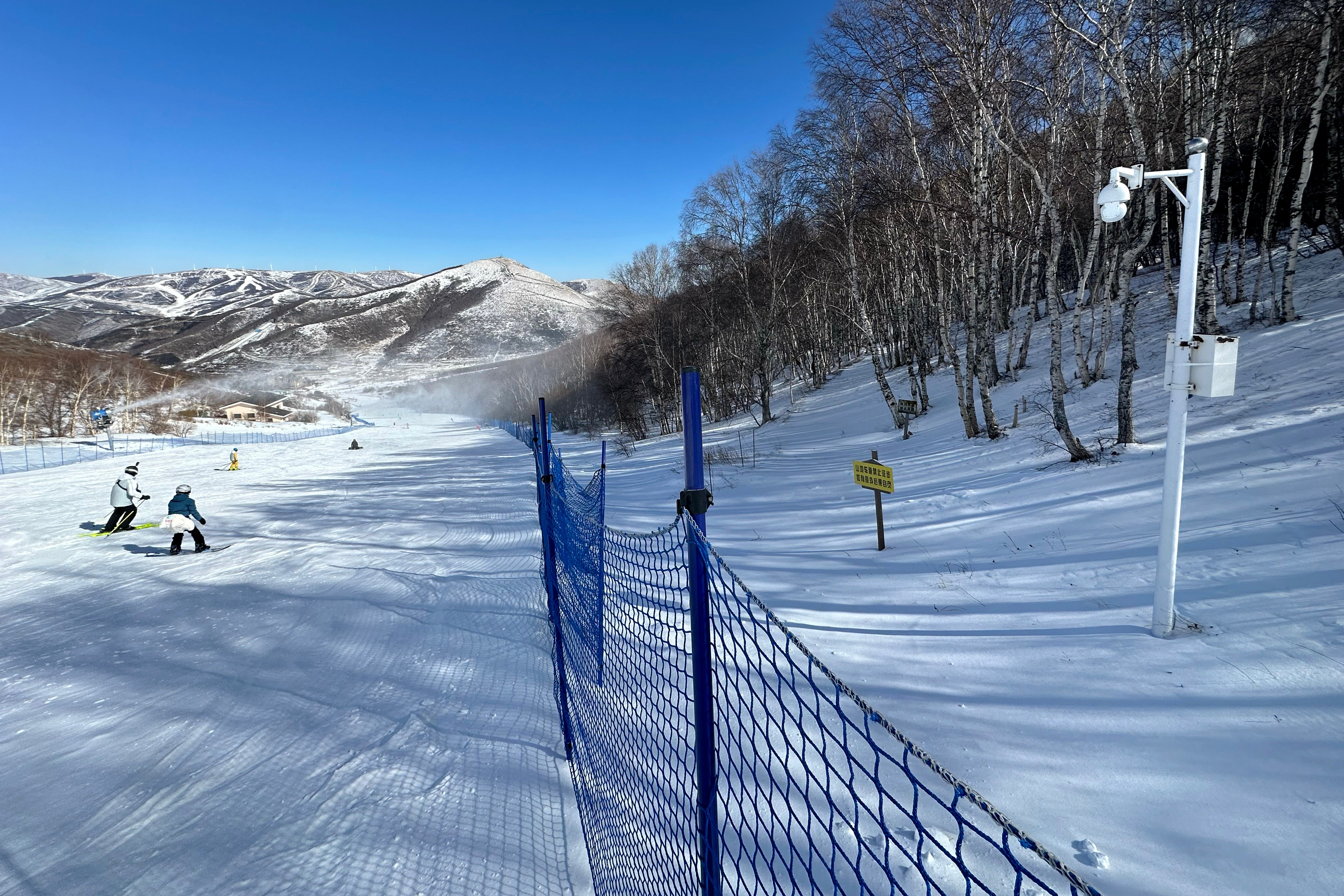 <p>A surveillance camera installed in a forest by a ski slope watches skiers and snowboarders in Chongli, China</p>